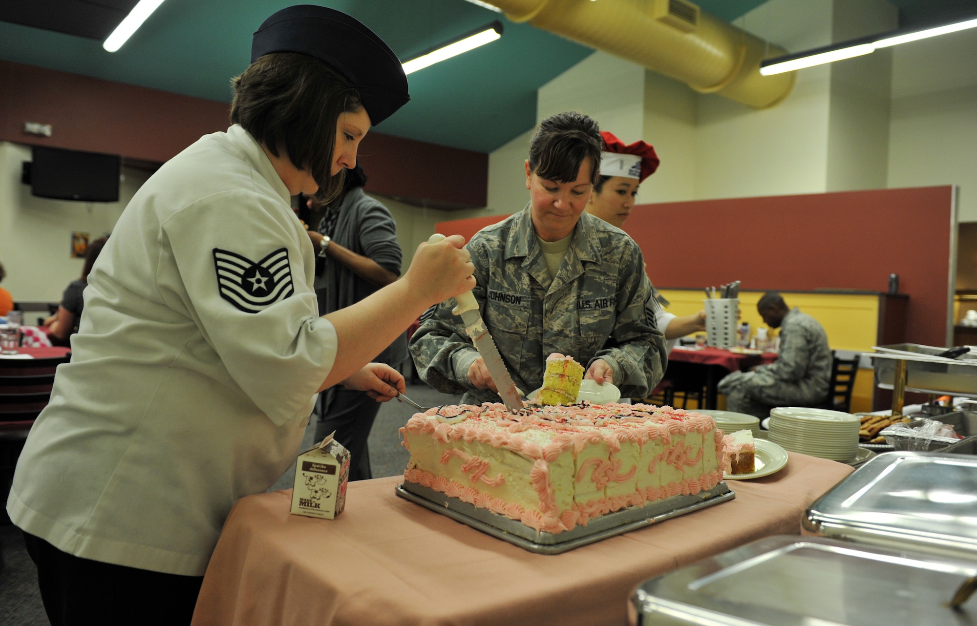 Tech. Sgt. Laurel Filbert, 509th Force Support Squadron Ozark Inn Food and Service Production Manager, and Senior Master Sgt. Robyn Johnson, Airmen and Family Readiness Center NCO, slice a piece of cake during the Hearts Apart Thanksgiving dinner Nov. 15 at Whiteman Air Force Base, Mo. Hearts Apart, a program designed to keep families connected while a spouse is deployed, is just one of many offered by the A&FRC. (U.S. Air Force photo/Heidi Hunt)