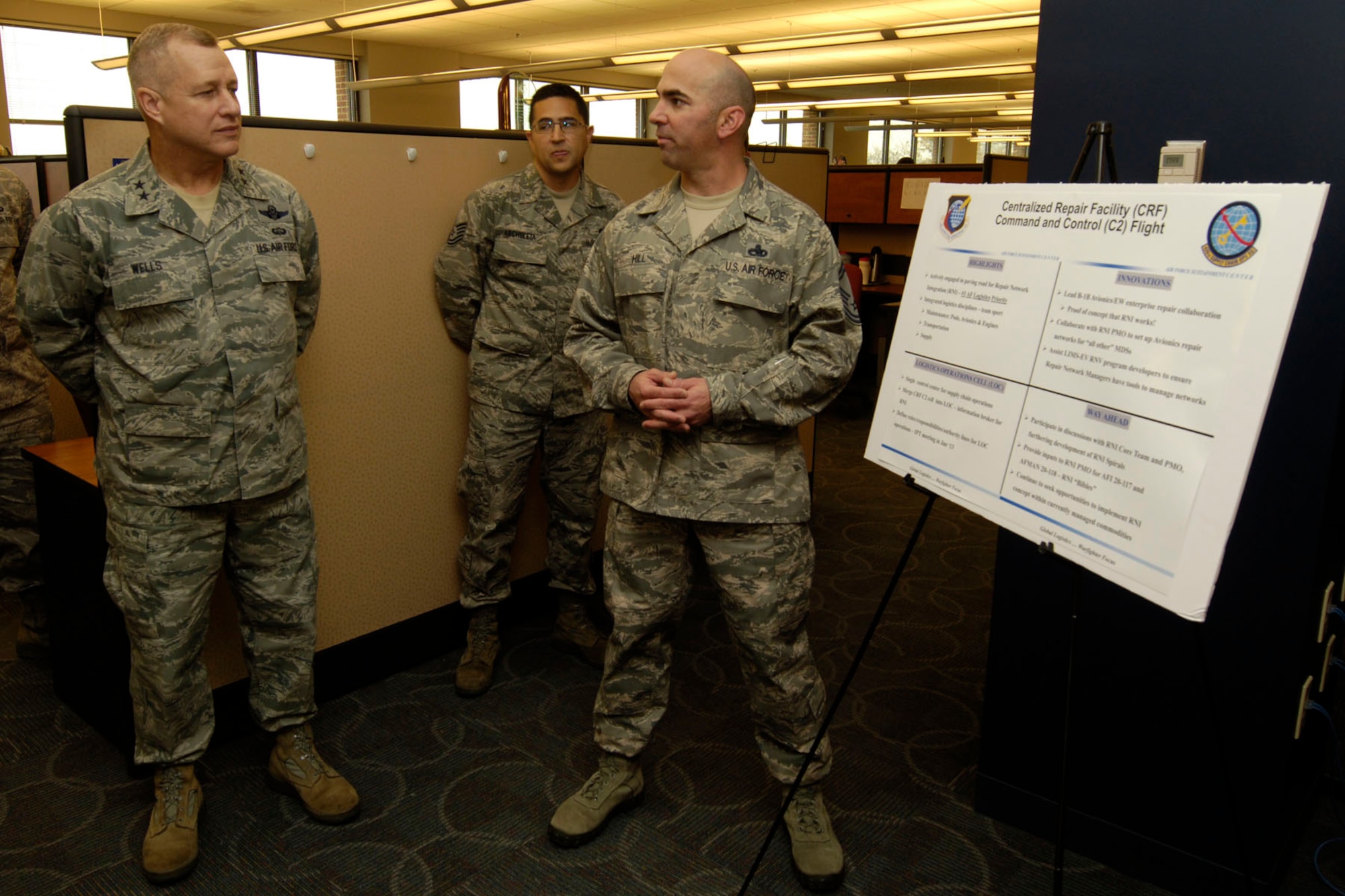 U.S. Air Force Maj. Gen. Lawrence Wells (left), 9 Air Force commander, listens as Senior Master Sgt. Dwayne Hill, 439th Supply Chain Operations Group Centralized Repair Facility Command and Control superintendent, gives the general a mission brief at Langley Air Force Base, Va., Dec. 5, 2012. The general visited Langley to better understand the assigned tenant units and their role at Langley. (U.S. Air Force photo by Staff Sgt. Jeff Nevison/Released)