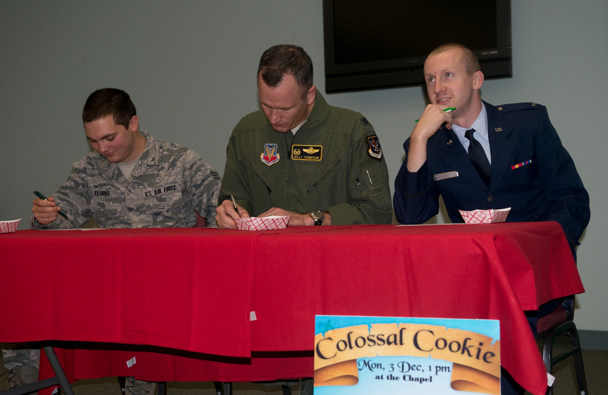 U.S. Air Force Senior Airman Michael Florio, 23d Operation Support Squadron intelligence targets journeyman, Col. Billy Thompson, 23d Wing commander, and 2nd Lt. Jacob Cannon, 23d Force Support Squadron deputy community services flight commander, tally the final scores during the Colossal Cookie competition at Moody Air Force Base, Ga., Dec. 3, 2012. The judges graded each cookie on taste, creativity and presentation. (U.S. Air Force photo by Airman 1st Class Paul Francis/Released)
