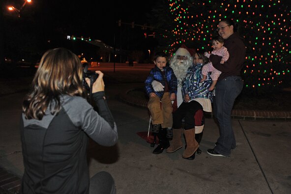 Santa Claus poses for a photo with a family during the annual tree lighting ceremony on Seymour Johnson Air Force Base, N.C., Dec. 3, 2012. Santa assisted with the holiday tree lighting and provided a photo opportunity for children during the event. (U.S. Air Force photo/Airman 1st Class John Nieves Camacho/Released)