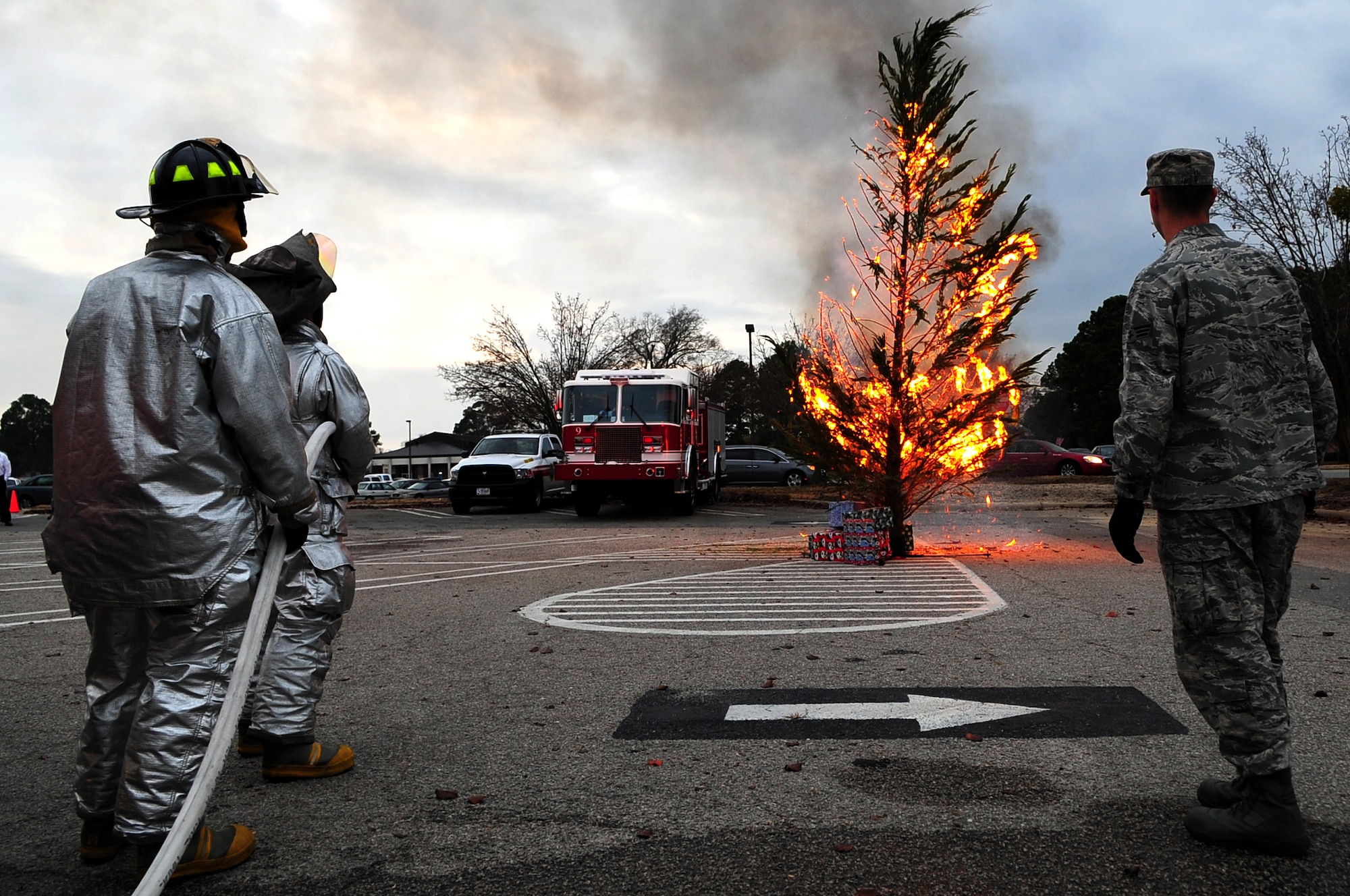 From left to right, U.S. Air Force Airman 1st Class Scottie Leeson , Airman Brendon Shonka and Senior Airman Daniel Gough, 4th Civil Engineer Squadron fire fighters, watch as a tree burns during a holiday safety demonstration at the Exchange on Seymour Johnson Air Force Base, N.C., Dec. 5, 2012. (U.S. Air Force photo/Airman 1st Class Mariah Tolbert/Released)