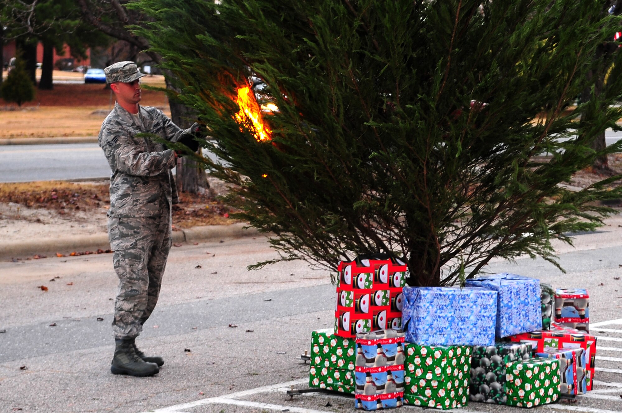 U.S. Air Force Senior Airman Daniel Gough, 4th Civil Engineer Squadron fire fighter, sets fire to a Christmas tree during a safety demonstration at the Exchange on Seymour Johnson Air Force Base, N. C., Dec. 5, 2012. The 4th CES fire emergency services flight demonstrated what could happen to a tree that was near a heat source. (U.S. Air Force photo/ Airman 1st Class Mariah Tolbert/Released)
