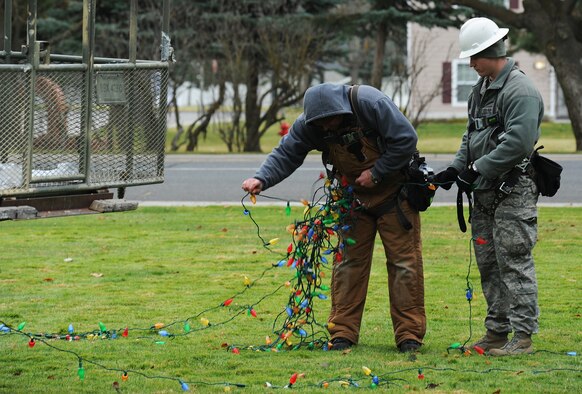 Shondel Rohn and Senior Airman Ryan Elliot untangle lights for a tree in front of the base chapel Nov. 28, 2012, in preparation for the annual wing tree lighting ceremony at Fairchild Air Force Base, Wash. Rohn is an electrical systems technician and Elliot is an electrician both with the 92nd Civil Engineer Squadron. (U.S. Air Force photo by Senior Airman Dennis Ayres)