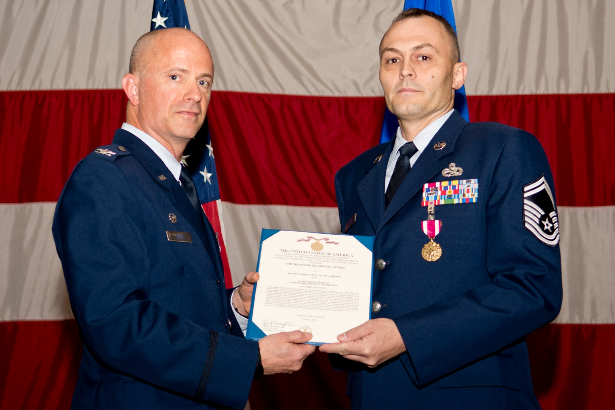 U.S. Air Force Col. Jonathan Ellis, 307th Bomb Wing commander, presents the Meritorious Service Medal to Master Sgt. Clifford Brown during a Commander's Call, Dec. 2, 2012, Barksdale Air Force Base, La. Brown distinguished himself in support of the 917th Aircraft Maintenance Squadron Total Force Integration and for his efforts while deployed in support of Operation Enduring Freedom. (U.S. Air Force photo by Master Sgt. Greg Steele/Released)