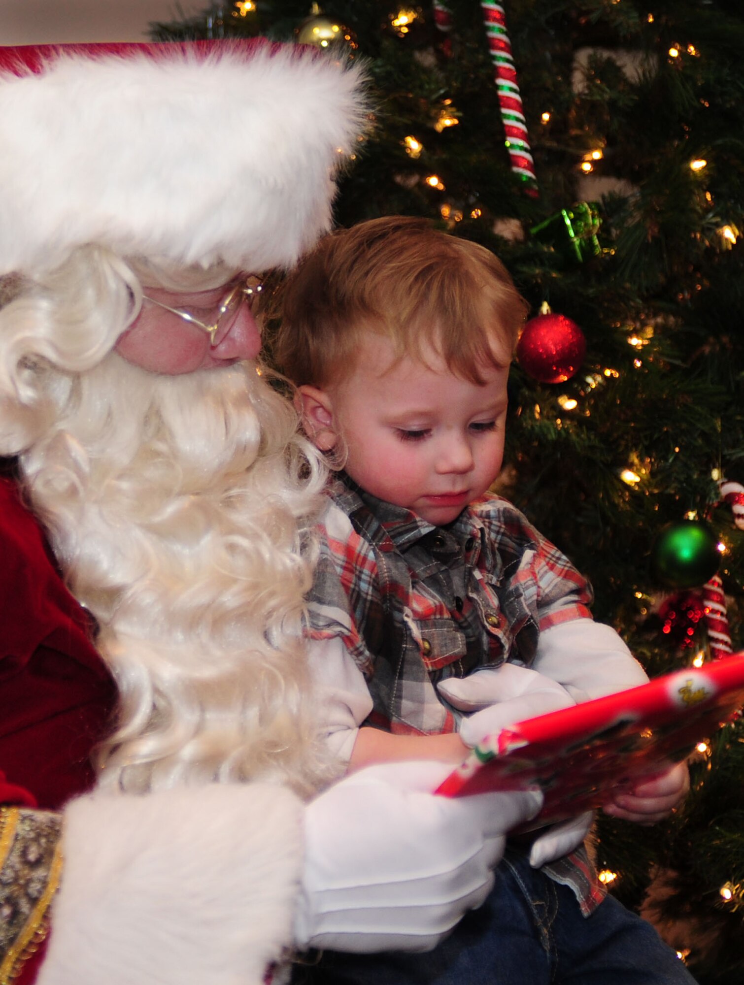 Santa Claus hands a gift to a child during the Hearts Apart deployed spouse dinner at Cannon Air Force Base, N.M., Dec. 4, 2012. The dinner was part of the Hearts Apart program which offers spouses of deployed, temporary duty assignment, or remote tour military members a chance to relax and connect with other families going through the same experience. (U.S. Air Force photo/Airman 1st Class Ericka Engblom)