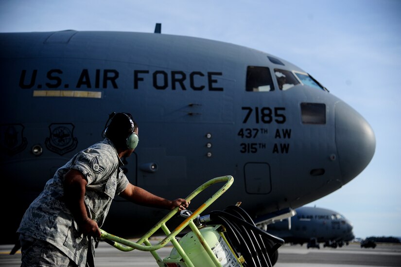 Staff Sgt. Norris Lewis, 437th Aircraft Maintenance Squadron crew chief, pushes a fire extinguisher into position as a C-17 Globemaster III arrives at the parking ramp, Dec. 5, 2012, at Joint Base Charleston - Air Base, S.C. After flight, maintenance crew chiefs ensure the aircraft remains operationally ready. (U.S. Air Force photo/Staff Sgt. Rasheen Douglas)