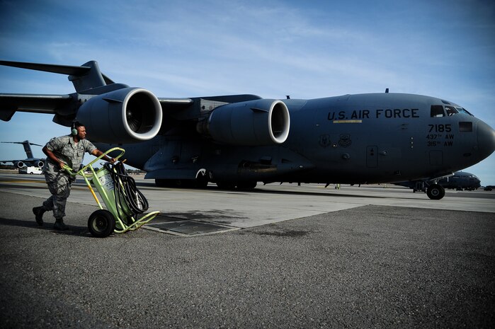 Staff Sgt. Norris Lewis, 437th Aircraft Maintenance Squadron crew chief, pushes a fire extinguisher into position as a C-17 Globemaster III arrives at the parking ramp, Dec. 5, 2012, at Joint Base Charleston - Air Base, S.C. After flight, maintenance crew chiefs ensure the aircraft remains operationally ready. (U.S. Air Force photo/Staff Sgt. Rasheen Douglas)