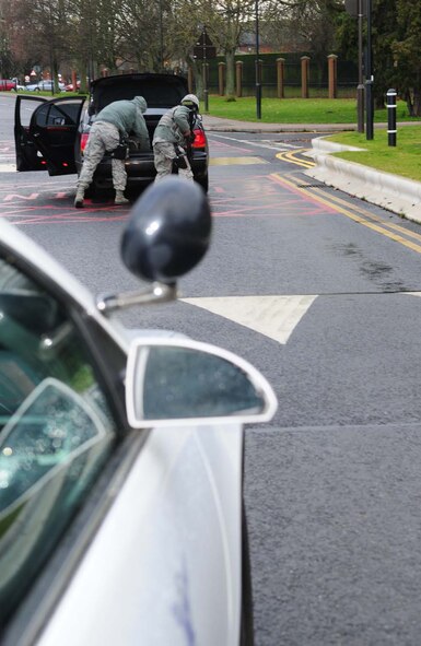 Members of the 100th Security Forces Squadron search a suspicious vehicle after a gate-runner drove illegally on base Dec. 4, 2012, during an operational readiness exercise at RAF Mildenhall, England. The gate-runner and passengers, played by 100th SFS members, drove the wrong way through Gate 17 then took off with a suspicious package, which they abandoned outside building 591. Patrol cars responded quickly and the patrolmen apprehended and handcuffed all the suspects. The ORE is one of many exercises in preparation for a combined unit inspection in 2013. (U.S. Air Force photo by Karen Abeyasekere/Released)