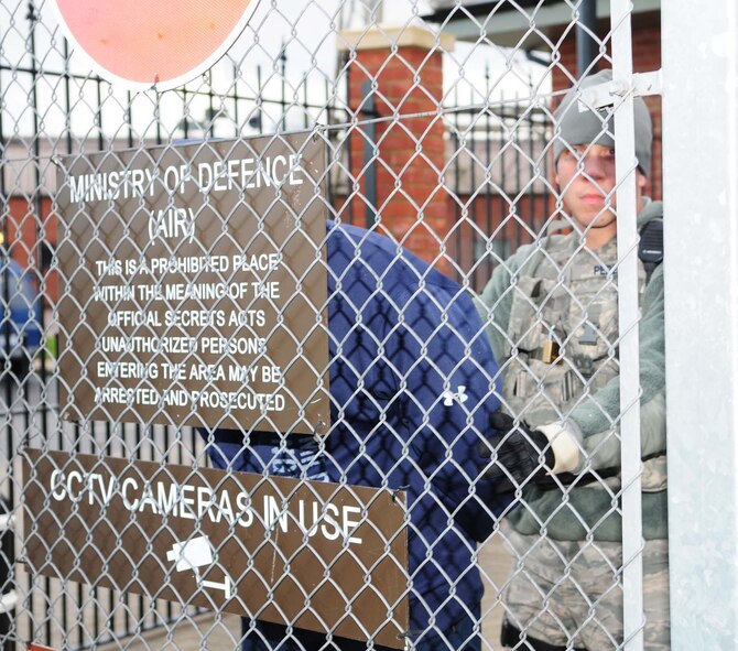 Senior Airman Samuel Perez, right, 100th Security Forces Squadron response force leader, from Plainfield, Conn., holds a handcuffed suspect against the fence after a car illegally accessed Gate 17 Dec. 4, 2012, during an operational readiness exercise at RAF Mildenhall, England. All three suspects, played by 100th SFS members, were apprehended and 100th SFS patrolmen stopped traffic and set up a cordon after the scenario turned into a bomb threat because the driver left a suspicious package outside building 591. Those working inside building 591 evacuated the facility and went to an alternate location. (U.S. Air Force photo by Karen Abeyasekere/Released)
