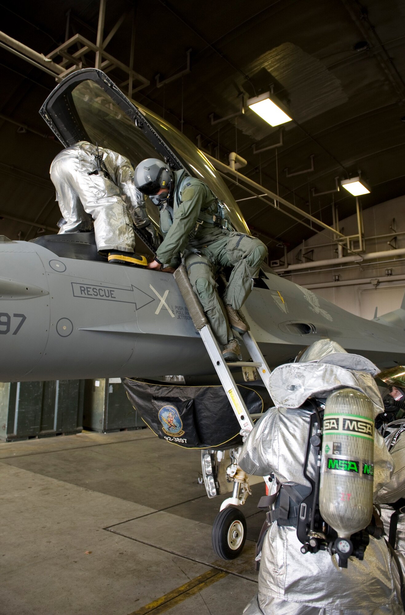 Firefighters from the 35th Civil Engineer Squadron help a pilot egress from an F-16 Fighting Falcon during a rescue training scenario, Dec. 5, 2012, during an Operational Readiness Exercise at Misawa Air Base, Japan. The scenario simulated smoke in the cockpit and an unconscious pilot. A three-man firefighting crew made entry into the Harden Aircraft Shelter to safely remove the pilot from the aircraft. (U.S. Air Force by Staff Sgt. Jess Lockoski)
