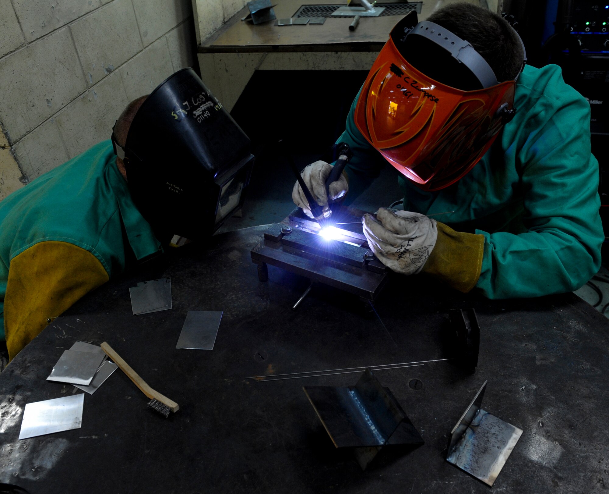 U.S. Air Force Col. Brian McDaniel, 18th Wing vice commander, listens while Staff Sgt. Justin Costanzo, 18th Equipment Maintenance Squadron aircraft metals technology craftsman, gives him tips and advice while he practices his tungsten-electrode inert gas welding technique on Kadena Air Base, Japan, Dec. 6, 2012. TIG welding is the process of blending together reactive metals such as magnesium and aluminum. During his visit to the 18th Equipment Maintenance Squadron, Airmen taught the commander how to do specific welding techniques. McDaniel said he wanted to learn how to weld because his father used to weld and would always boast about how good he was, so he wanted to try it out himself to show that he could do it too. (U.S. Air Force photo/Airman 1st Class Justin Veazie)