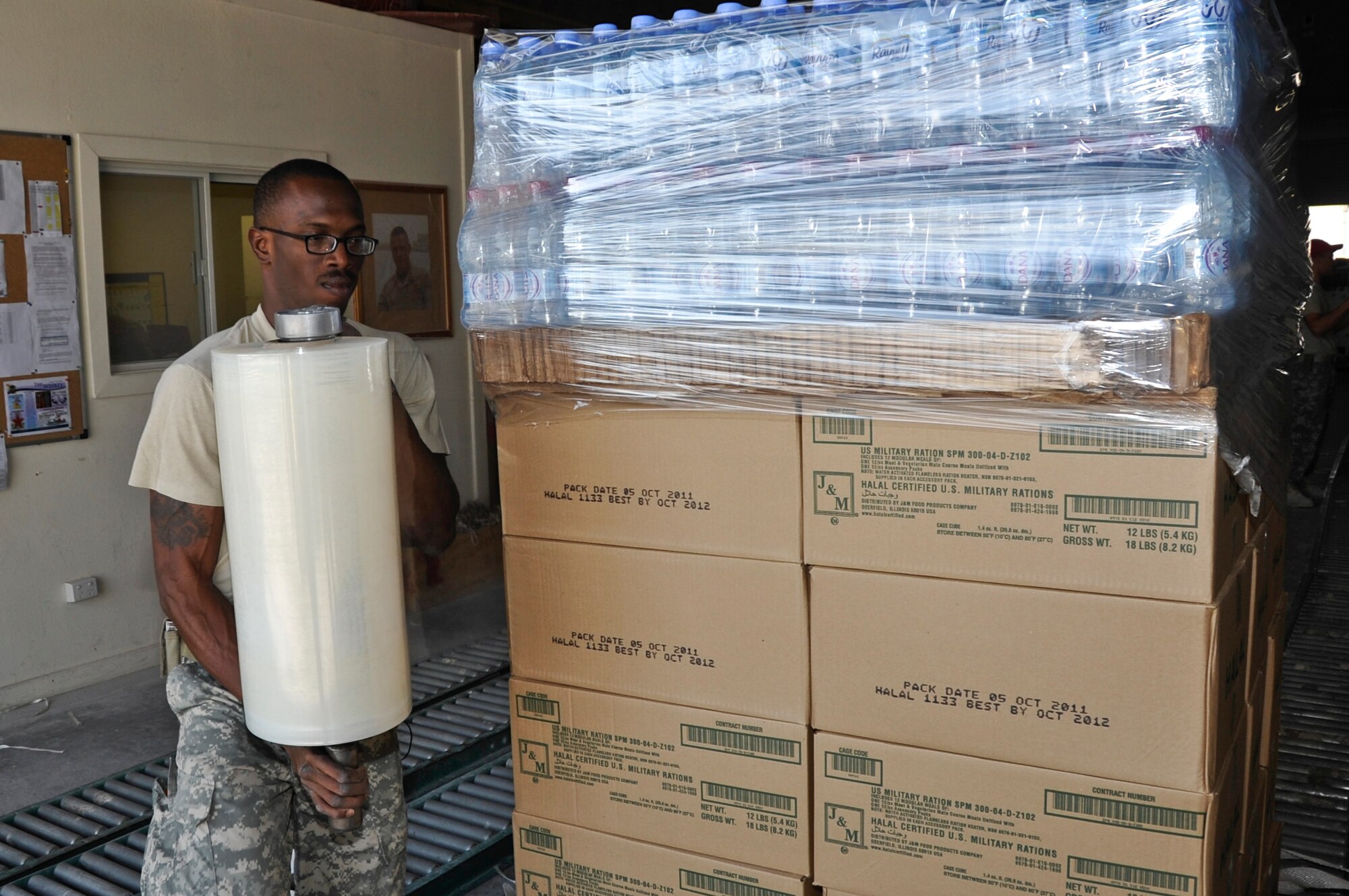 SOUTHWEST ASIA - Army Spc. Neilon Burton, 421st Quartermaster Company Detachment 4 airdrop specialist, wraps the stacked bundle in plastic before securing the low-cost, low-altitude airdrop cargo assembly Dec. 4. The detachment has airdropped more than 7,400 bundles, weighing more than 12 million pounds to ground troops in Afghanistan since the beginning of 2012. Burton, a native of the U.S. Virgin Islands, is deployed from Fort Valley, Ga. (U.S. Air Force photo/Senior Airman Bryan Swink)