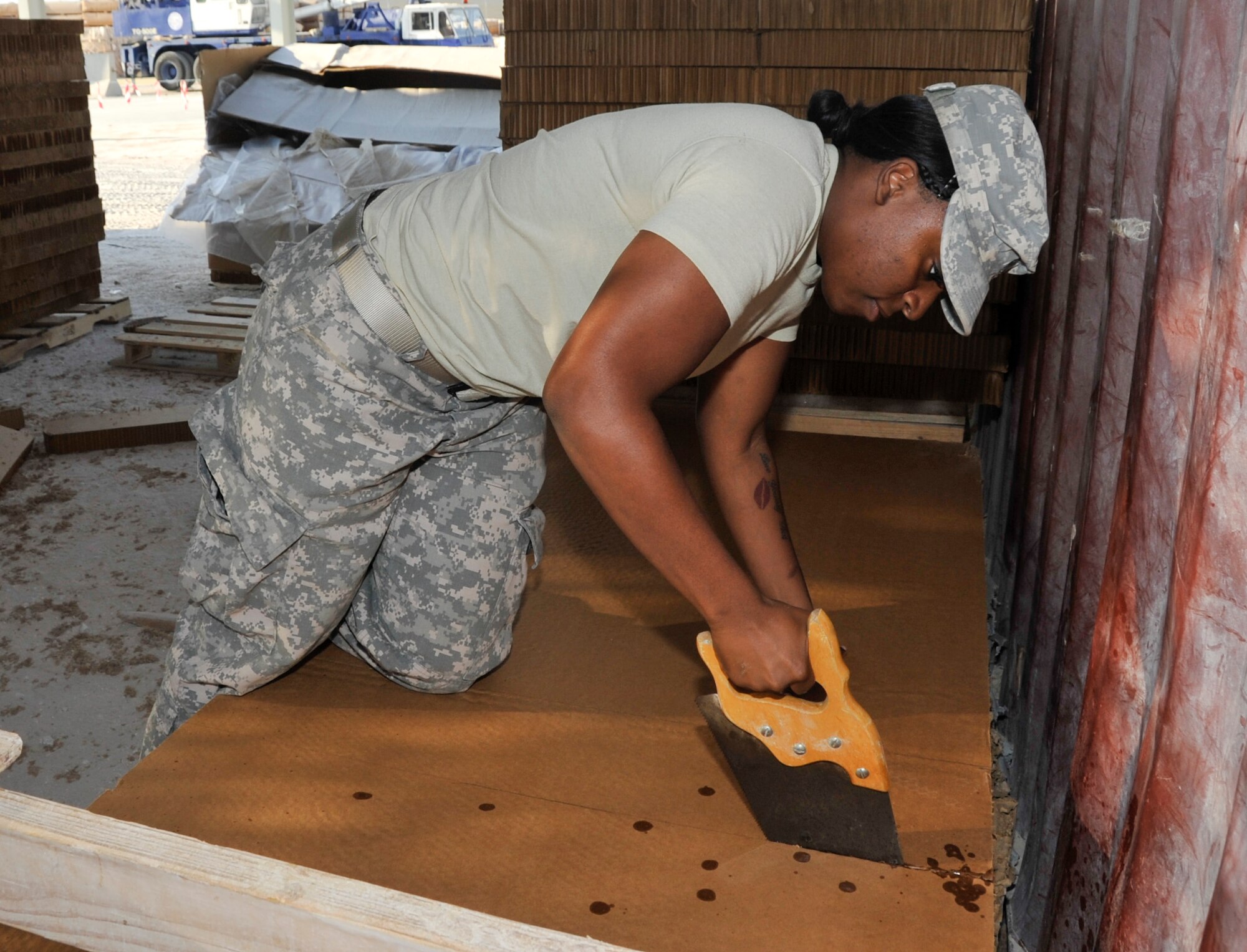 SOUTHWEST ASIA - Army Spc. Tammy Bradley, 421st Quartermaster Company Detachment 4 supply specialist, uses a handsaw to cut through layers of honeycomb cardboard Dec. 4. The honeycomb is cut to exact measurements and placed at the base of the load, which will be airdropped to support ground troops in Afghanistan. Honeycomb acts as a buffer to absorb the impact after the load is falling between 28 and 49 feet per second when it hits the ground. Bradley, a native of Valdosta, Ga., is deployed from Fort Valley, Ga. (U.S. Air Force photo/Senior Airman Bryan Swink)
