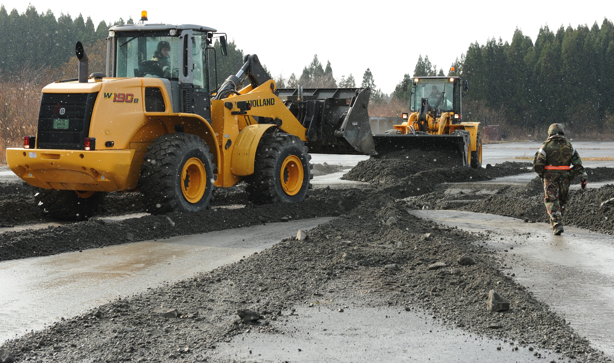 Two front-end loaders from the 35th Civil Engineer Squadron airfield damage repair flight clear debris from a simulated missile impact crater during an Operational Readiness Exercise at Misawa Air Base, Japan, Dec. 5, 2012. The mock runway area on Security Hill gives the flight the ability to practice their craft without damaging the active runway or taxiways. (U.S. Air Force by Staff Sgt. Jess Lockoski)