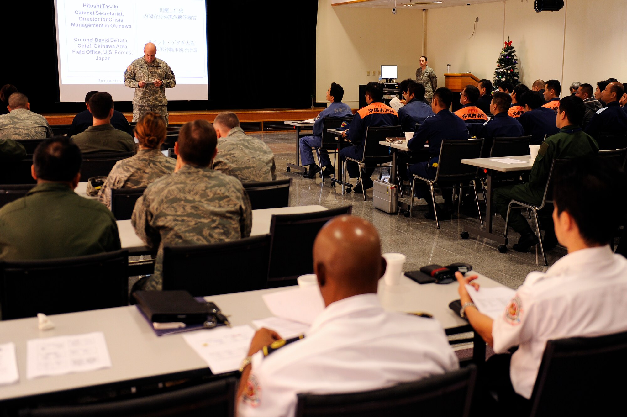 Service members from all U.S. military branches on Okinawa as well as Okinawan emergency responders and government officials listen as U.S. Army Col. David DeTata, U.S. Forces, Japan's Okinawa Area Field Office chief, makes an opening statement during the joint table-top exercise at the Schilling Community Center on Kadena Air Base, Japan, Dec. 4, 2012. During the exercise, participants simulated a U.S. military aircraft crash in Okinawa city and discussed civilian injuries, the notification system and rescue activities. Roughly 70 people, including officials from the Okinawa Prefectural Police, Okinawa City Fire Department and all U.S. military Services participated in the training. (U.S. Air Force photo/Senior Airman Maeson L. Elleman/released)
