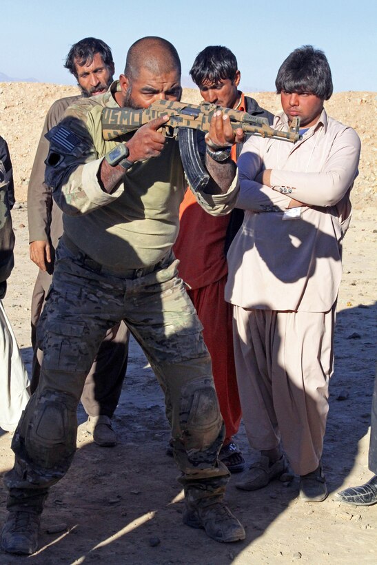 A special operations team member demonstrates the proper standing shooting position with a AK-47 to Afghan local police recruits during a marksmanship class on their first day of training in Afghanistan's Farah province, Dec. 1, 2012.