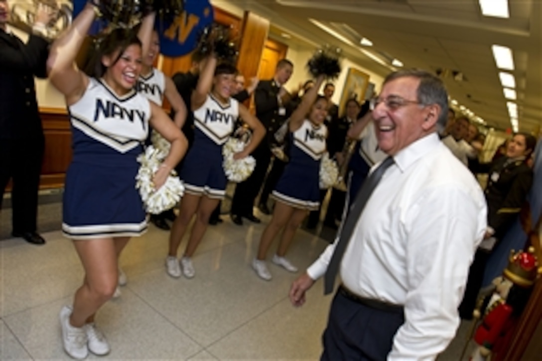 Defense Secretary Leon E. Panetta greets the U.S. Naval Academy Midshipmen cheerleaders and band during a pep rally held in the halls of the Pentagon, Dec. 6, 2012. Each year before the historic Army-Navy football game, which is set for Dec. 8, 2012, the Navy and Army pep squads conduct a rally at the Pentagon and visit the offices of senior Defense Department leaders. 