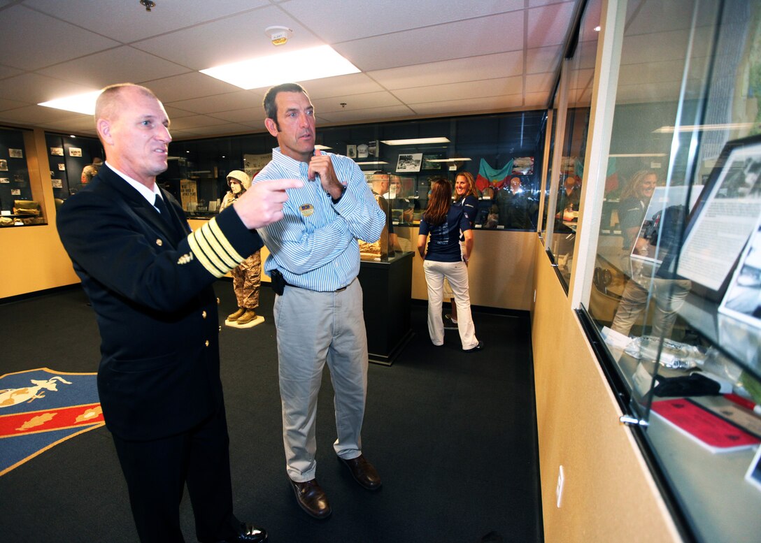 Navy Captain Michael Eby, the commanding officer of Field Medical Training Battalion West, gives a short tour of the FMTB-West Museum to Sam Pelham, the Semper Fit deputy director, at Camp Pendleton, Calif., Nov. 30. Pelham visited FMTB-West to award the battalion with a $2,000 check from Marine Corps Community Services for outstanding volunteer work during the Hard Corps Race Series 2012. The battalion provided more than 200 volunteers during the Hard Corps Race Series 2012. The corpsmen who volunteered primarily provided medical assistance to competitors during and after the race.
