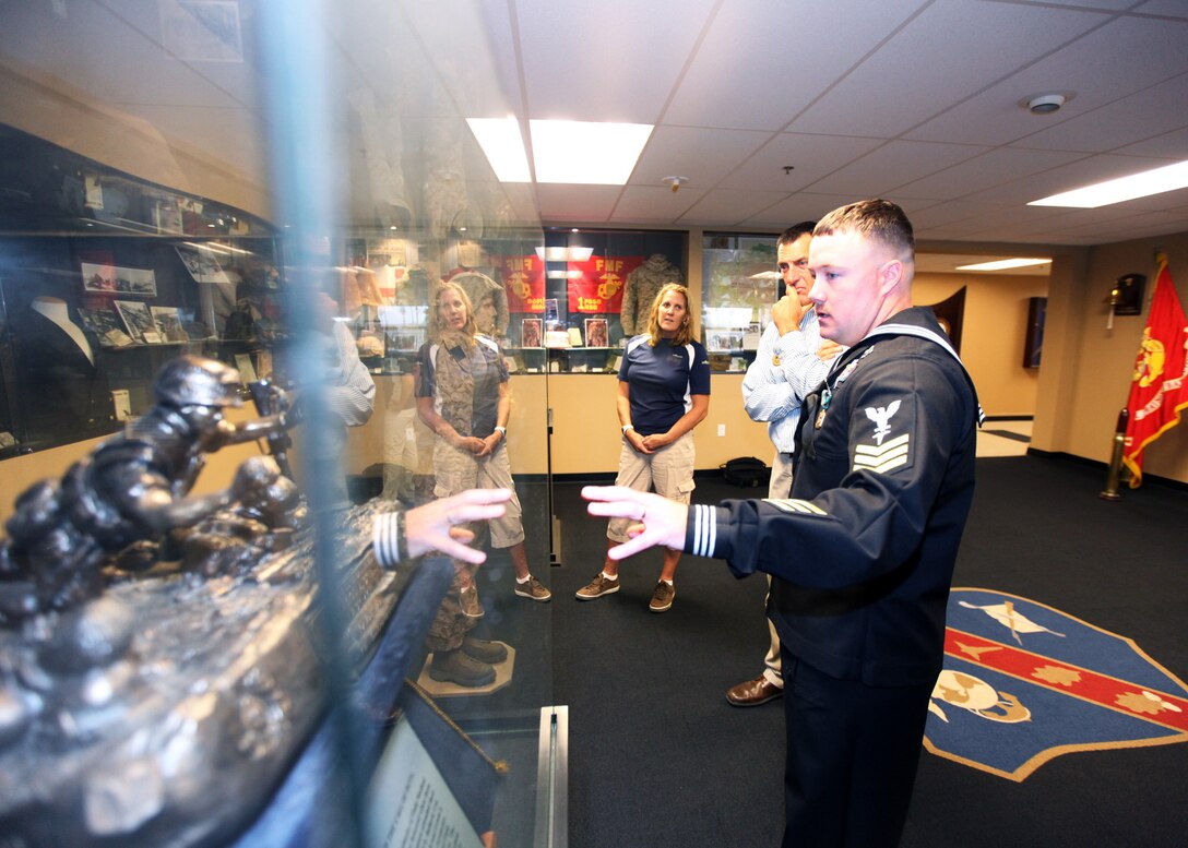 Petty Officer 1st Class Adam Clayton, a corpsman and instructor with Field Medical Training Battalion West gives a short tour of the FMTB-West Museum to Marine Corps Community Services staff members at Camp Pendleton, Calif., Nov. 30. The MCCS staff visited FMTB-West to award the battalion with a $2,000 check for outstanding volunteer work during the Hard Corps Race Series 2012. Marine Corps Community Services chose Clayton, who volunteered and attended each race as the volunteer coordinator, to receive the award on behalf of the battalion.