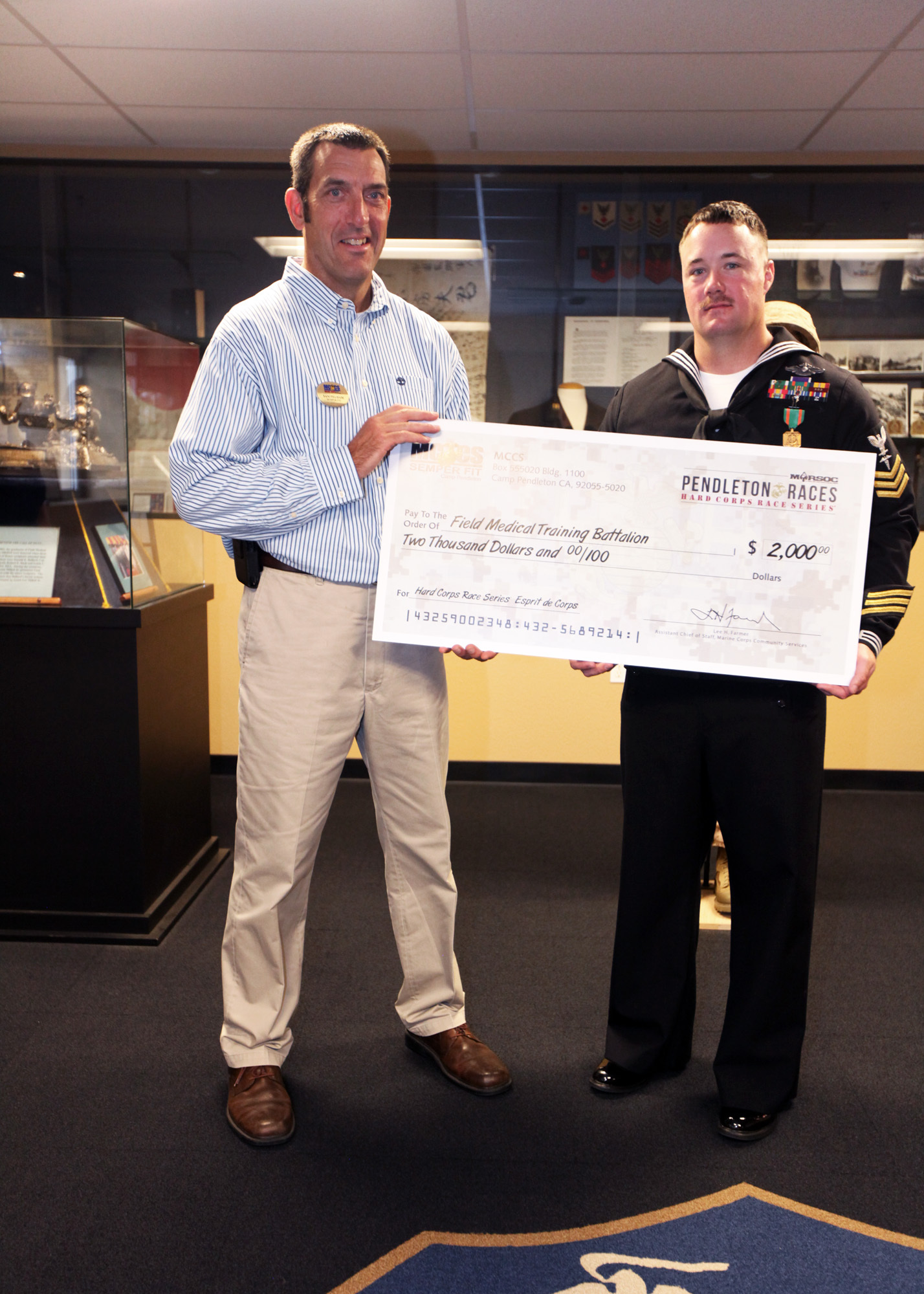 Sam Pelham, the Semper Fit deputy director, presents a $2,000 check to Field Medical Training Battalion West for outstanding volunteer work at Camp Pendleton, Calif., Nov. 30. FMTB-West provided more than 200 volunteers during the Hard Corps Race Series 2012. The corpsmen who volunteered primarily provided medical assistance to competitors during and after the race. Marine Corps Community Services chose Petty Officer 1st Class Adam Clayton, a corpsman and instructor with FMTB-West, to receive the award on behalf of the battalion and to recognize him for his efforts and involvement in the series.