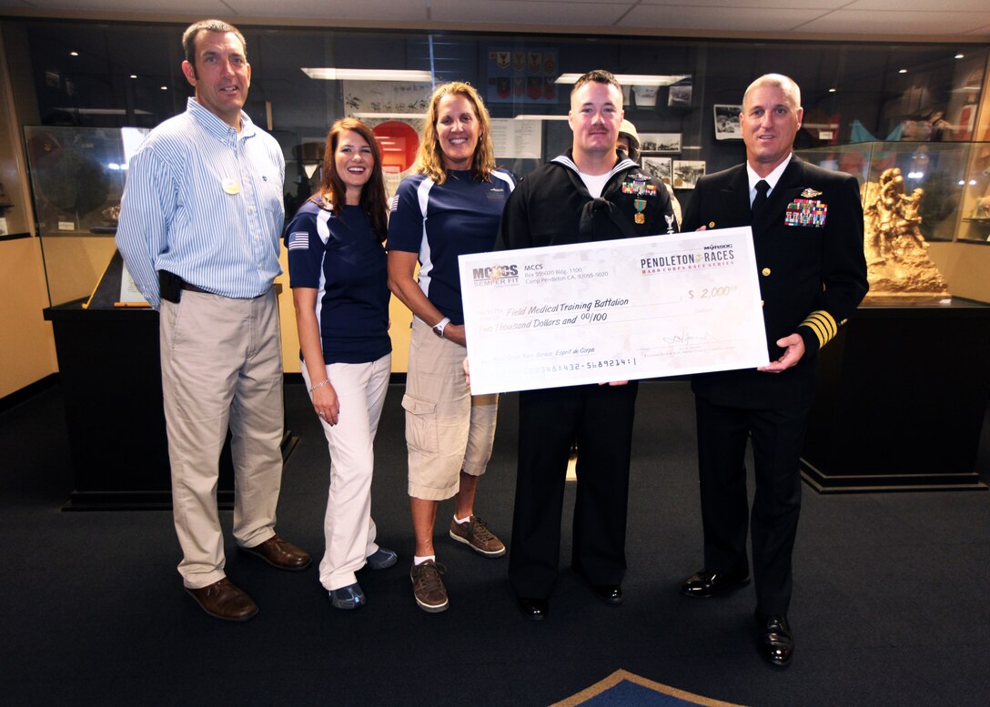 Marine Corps Community Services presents a $2,000 check to Field Medical Training Battalion West for outstanding volunteer work at Camp Pendleton, Calif., Nov. 30. FMTB-West provided more than 200 volunteers during the Hard Corps Race Series 2012. The corpsmen who volunteered primarily provided medical assistance to competitors during and after the race. Marine Corps Community Services chose Petty Officer 1st Class Adam Clayton, a corpsman and instructor with FMTB-West, to receive the award on behalf of the battalion and to recognize him for his efforts and involvement in the series.