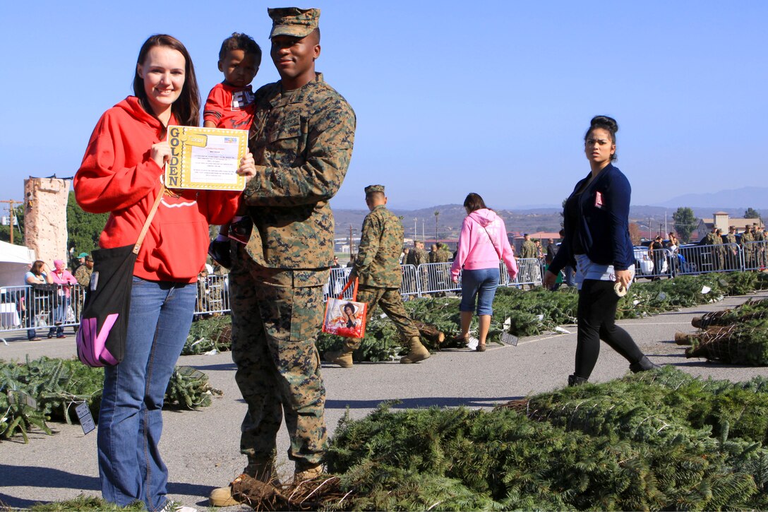 Lance Cpl. Anthony D. Wilson, a field radio operator with 9th Communications Battalion, his wife, Nikki S. Wilson, and their son Anthony Wilson Jr., gather for a photograph before picking a Christmas tree, during the 2012 Trees for Troops event here Dec. 7. The Wilson family was selected in a raffle to be the first family on Camp Pendleton to receive a Christmas tree.
