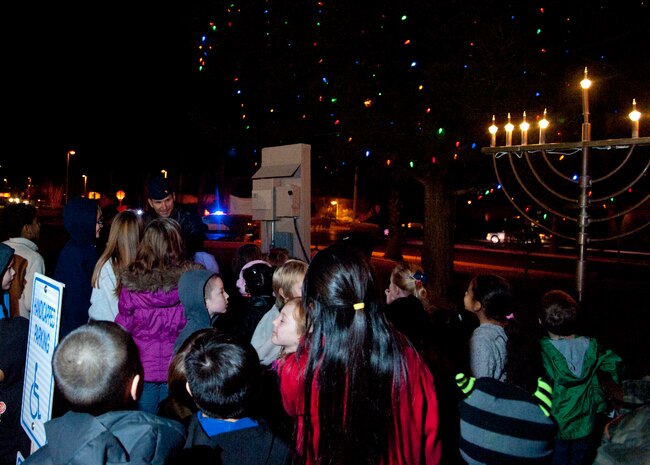 Col. Barry Cornish, 99th Air Base Wing commander, lights the Christmas tree and Hanukkah menorah with the help of children from the Nellis community at a ceremony Dec. 7, 2012, at Nellis Air Force Base, Nev. The children sang Christmas carols with the chapel's Praise Service Worship Team prior to lighting the tree. (U.S. Air Force photos by Master Sgt. Jason W. Edwards)