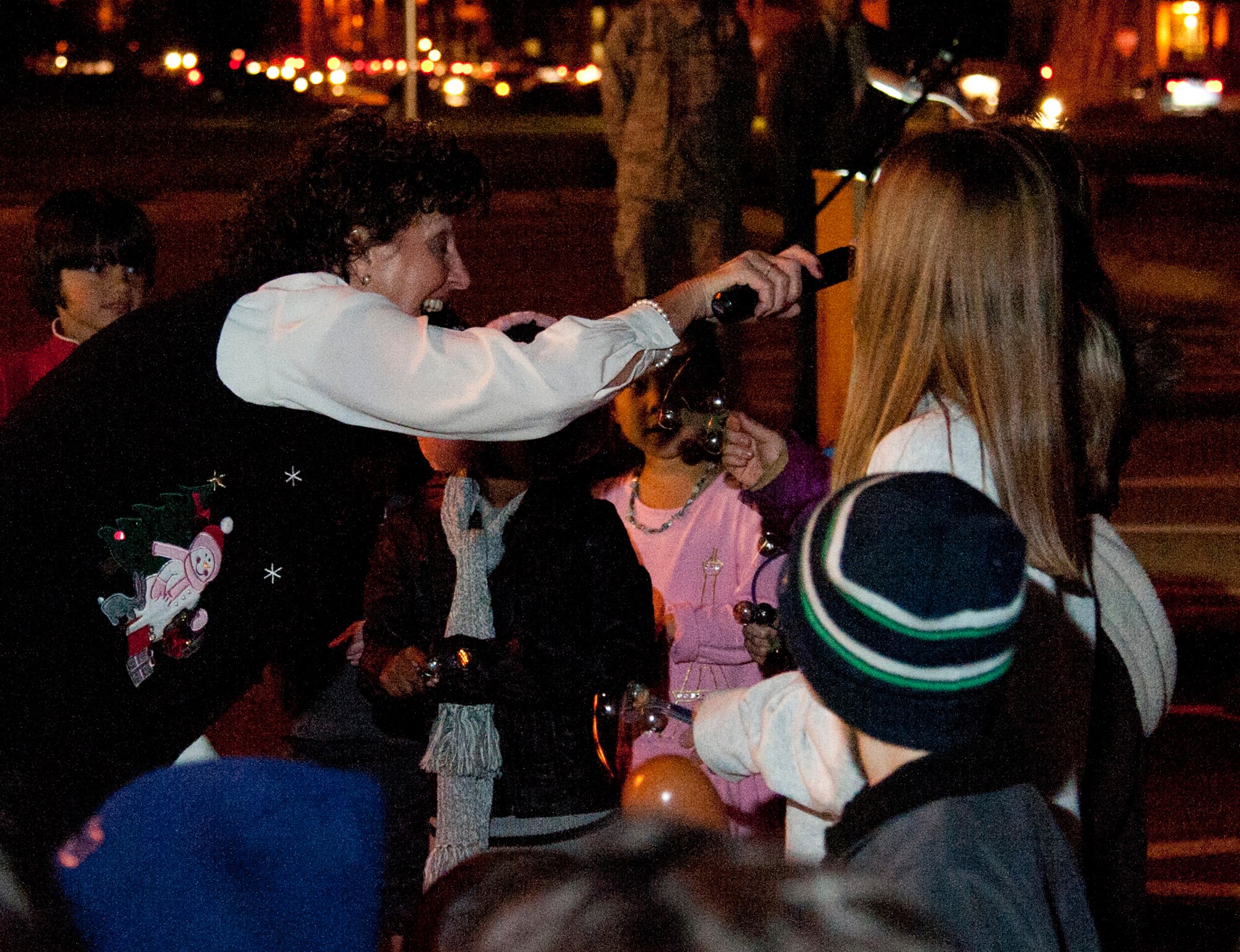 Kathy Rash, wife of Chaplain (Lt. Col.) Michael Rash, sings Christmas carols with Nellis children during the Menorah and Tree Lighting ceremony Dec. 7, 2012, at Nellis Air Force Base, Nev. Airmen and their families gathered outside the chapel to ring in the holiday season by singing songs and lighting the tree and menorah. (U.S. Air Force photo by Master Sgt. Jason W. Edwards)