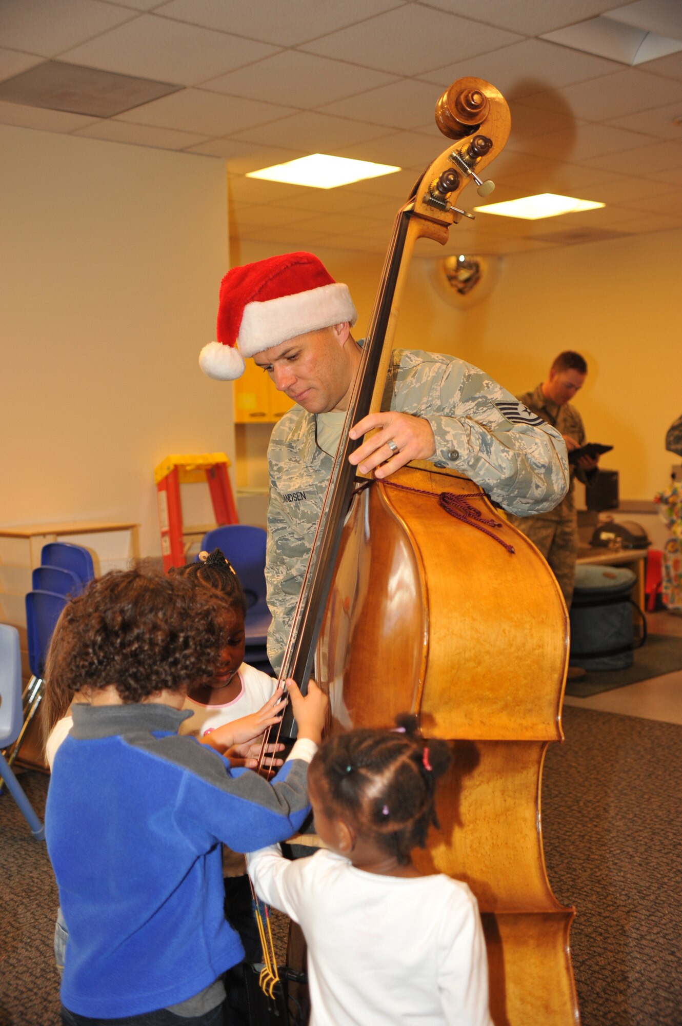 Air Force Tech. Sergeant Mark Frandsen, a musician with the Air Force Band of the Golden West demonstrates to children how to pluck the strings on an upright bass at the Child Development Center, Dec. 7.  The Band of the Golden West is stationed in the San Francisco Bay area at Travis Air Force Base, Calif. The only active duty Air Force band west of the Rockies, the band is comprised of 47 Airmen-musicians.   (Photo by Sarah Corrice)
