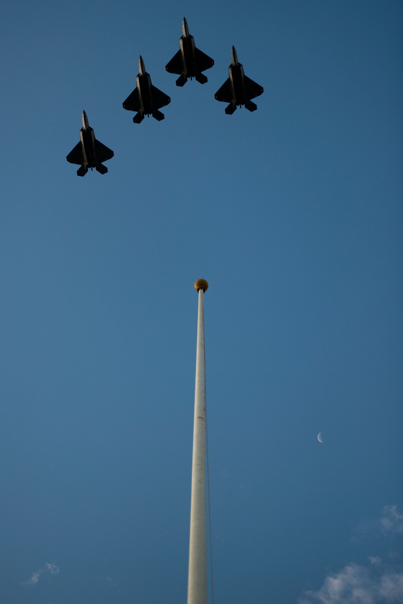 Four F-22 Raptors, assigned to the 19th and 199th Fighter Squadrons, Joint Base Pearl Harbor-Hickam, Hawaii, fly a missing-man formation over the Atterbury Circle flag pole during the 71st Anniversary Remembrance Ceremony, commemorating the attacks on Hickam Field Dec. 7, 1941. The fighter squadrons are a joint partnership between the active duty and Hawaii Air National Guard. The formation also flew over the Pearl Harbor ceremony. (U.S. Air Force photo/Staff Sgt. Mike Meares/Released)