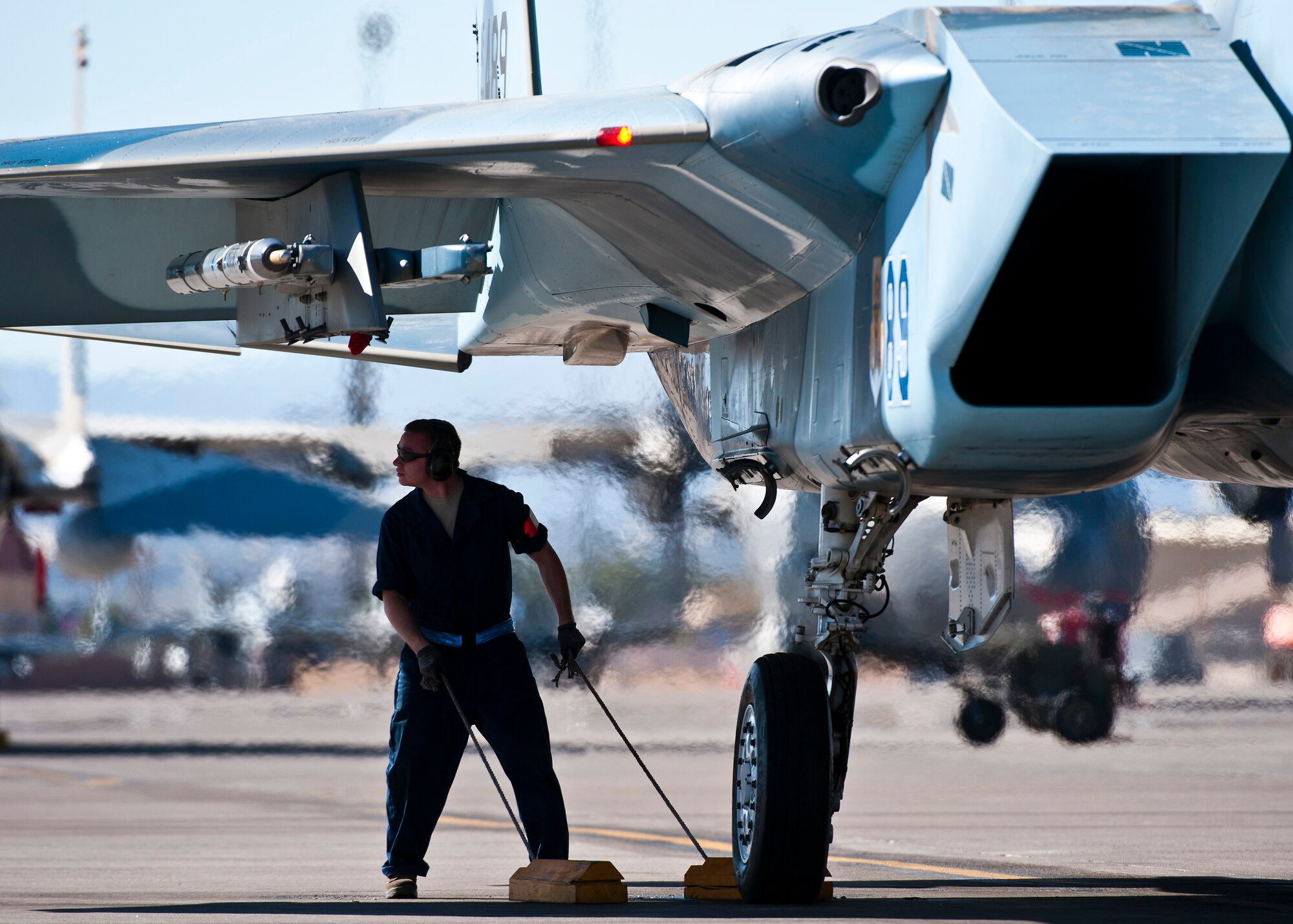 U.S. Air Force Senior Airman Walter Kautsky, Aerospace Propulsion Journeyman, pulls chaulks away from a F-15 Eagle during the Mission Employment Phase exercise Dec. 7, 2012, at Nellis Air Force Base, Nev. The exercise is hosted north of Las Vegas on the Nevada Test and Training Range--the U.S. Air Force's premier military training area with more than 12,000 square miles of airspace and 2.9 million acres of land. (U.S. Air Force photo/Senior Airman Brett Clashman)