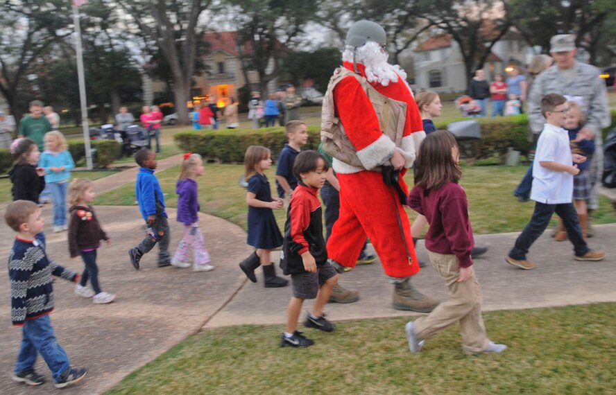 Team Barksdale children walk with Santa during the annual Holiday tree lighting ceremony on Barksdale Air Force Base, La., Dec. 6. Santa, returning from visiting deployed Airmen, asked the children what they wanted for Christmas and handed out candy cane. (U.S. Air Force photo/Senior Airman Kristin High)