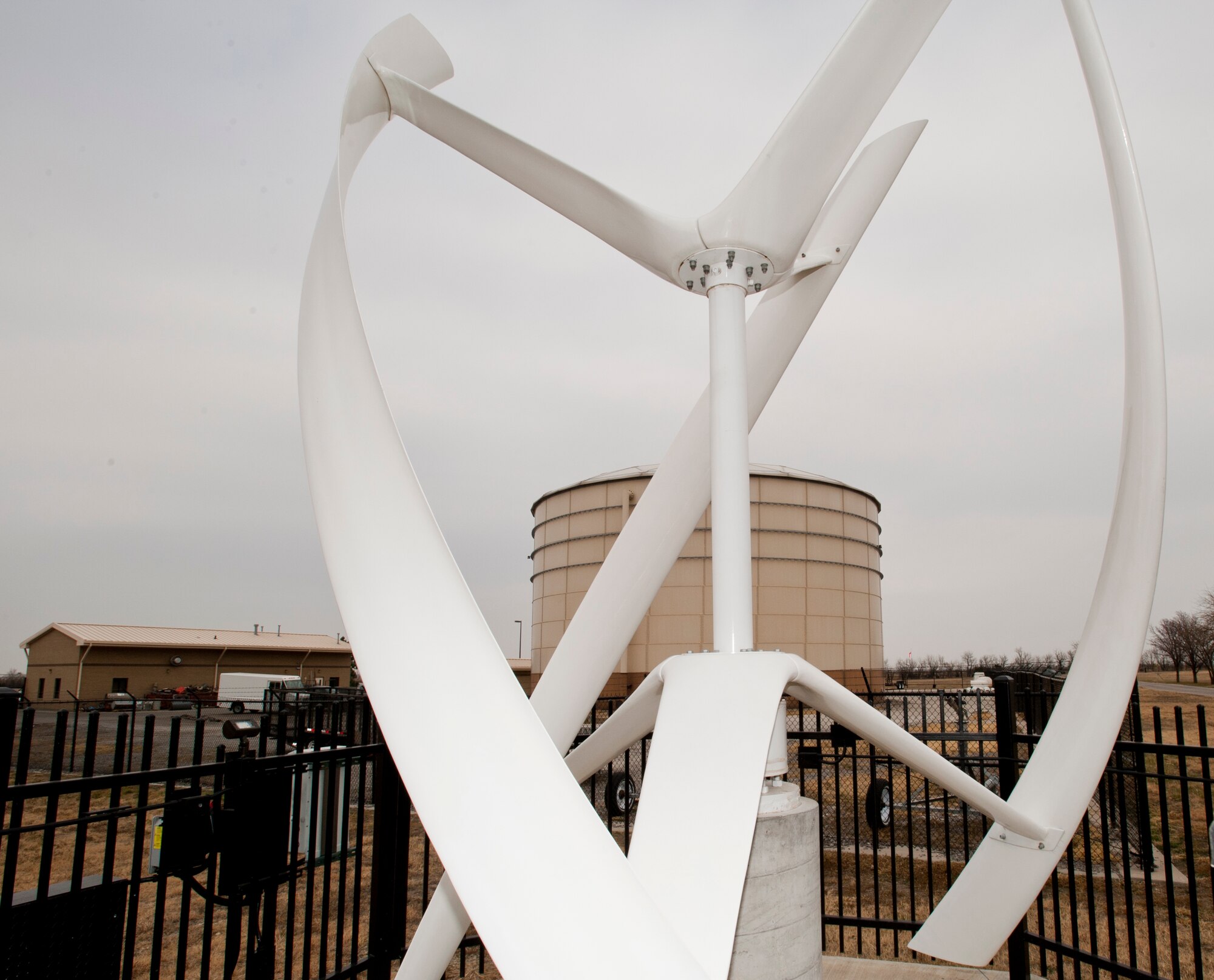 A wind turbine slowly rotates on a calm day Dec. 7, 2012, McConnell Air Force Base, Kan. The turbine, currently the only one on base, generates power for the 22nd Civil Engineer Squadron utility shop, pictured behind the turbine. The performance and benefit from this turbine is being studied to determine if more could be implemented around base. (U.S. Air Force photo/Airman 1st Class Victor J. Caputo)