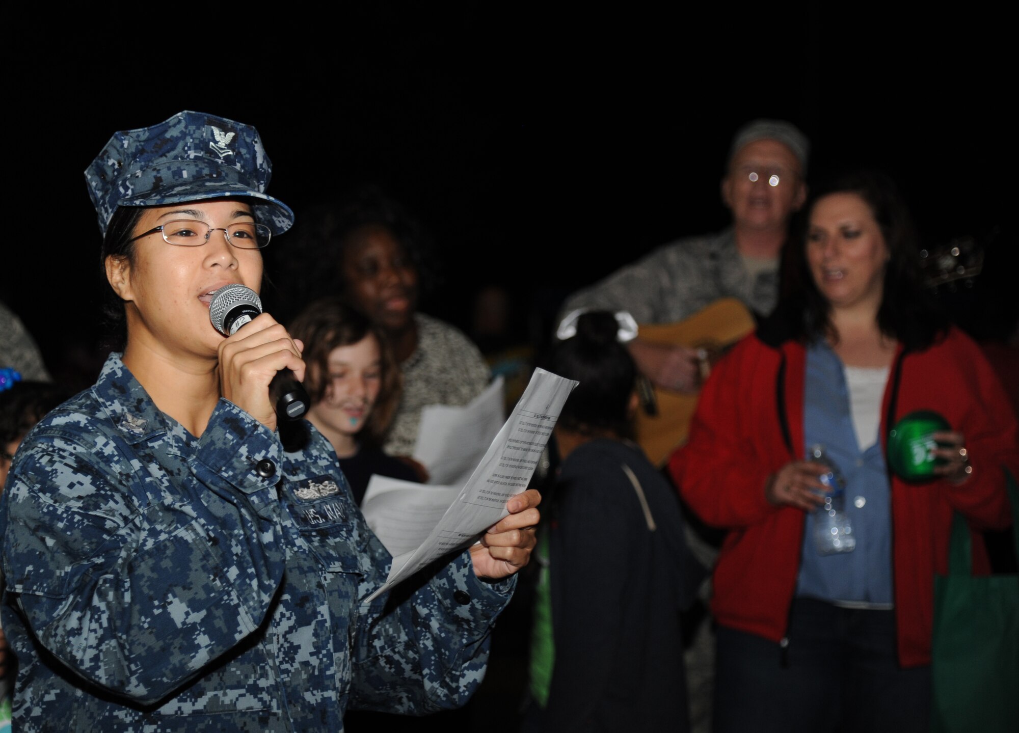 Petty Officer 2nd Class Mary Grace Castillo, Center for Naval Aviation Technical Training Unit, leads the audience in the holiday song, “Oh Gloria,” during Keesler’s annual Holiday in the Park, Dec. 6, 2012, at marina park, Keesler Air Force Base, Miss. The event also included a tree lighting ceremony, hay rides, visits with Santa and free food and beverages.  (U.S. Air Force photo by Kemberly Groue)