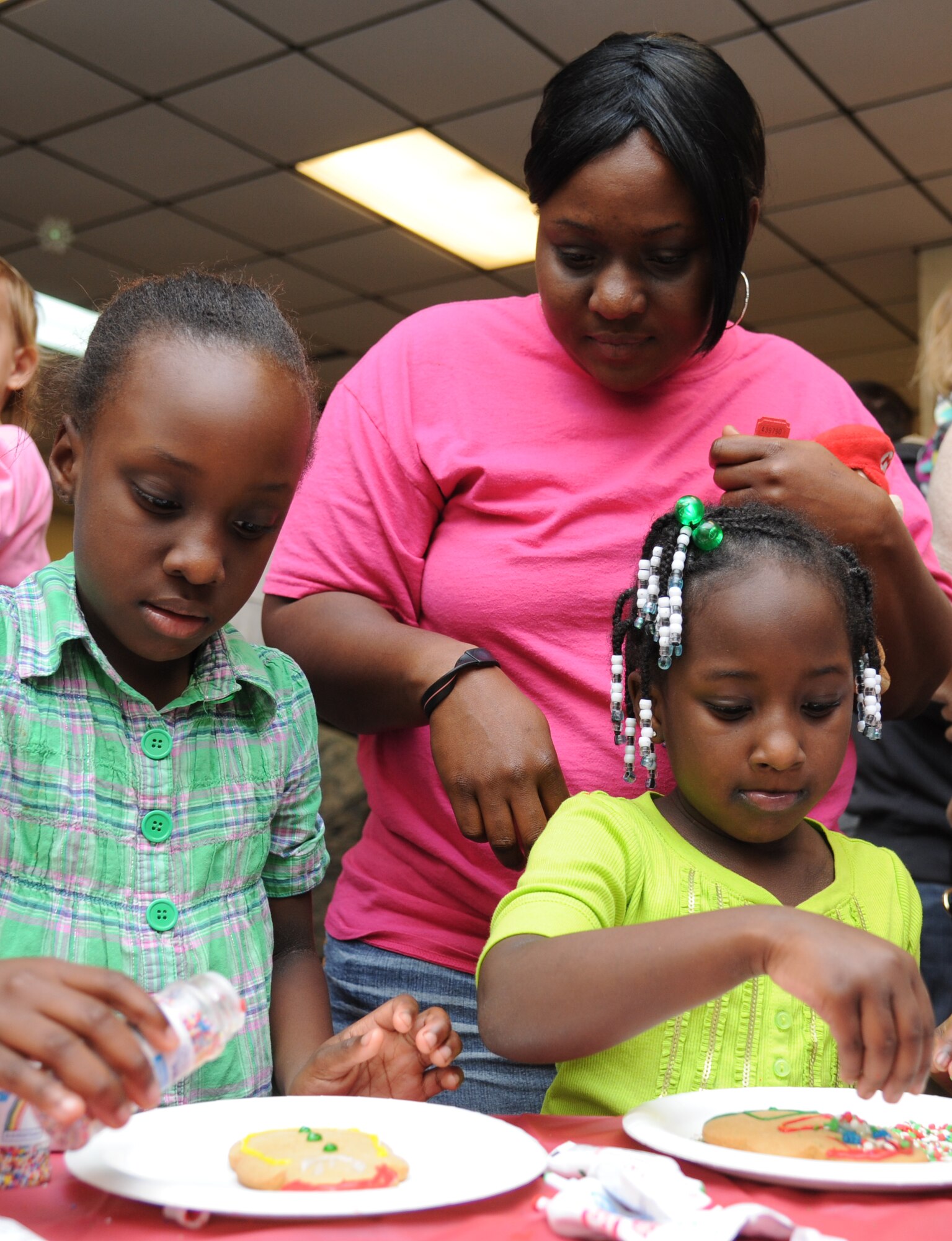 Tachanti Spencer, 8, her mother, Artoria, and her sister, Victoria, 6, decorate ginger bread cookies during Keesler’s annual Holiday in the Park, Dec. 6, 2012, at marina park, Keesler Air Force Base, Miss. The event aslo included a tree lighting ceremony, hay rides, holiday music, visits with Santa and free food and beverages.  (U.S. Air Force photo by Kemberly Groue)