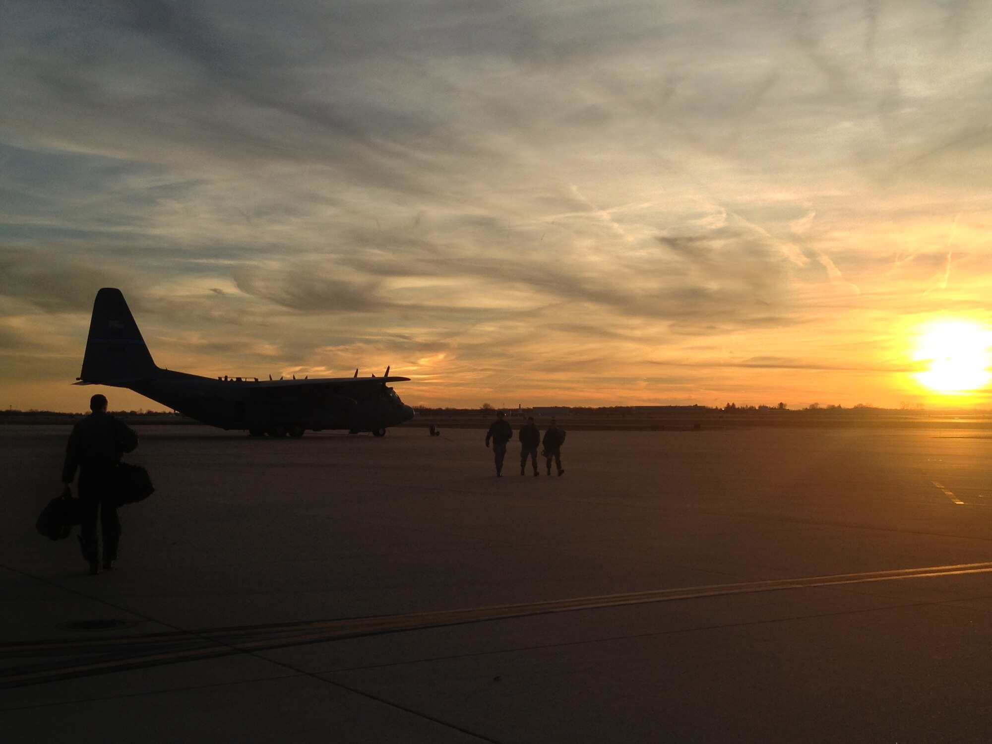 A Delaware Air National Guard C-130H model Hercules transport aircraft from the 142nd Airlift Squadron on the flight line at the New Castle ANG Base moments before sunset on Dec. 6, 2012 as aircrew walk to the aircraft for an evening tactical mission. The crew executed a container delivery system (CDS) drop to the Coyle Field Drop Zone in the N.J. Pine Barrens followed by a sandbag drop on the second route. The aircraft carried a large crew of three pilots, one navigator, four loadmasters and two flight engineers. (Air National Guard photo/Staff Sgt. Travis von Bodungen)