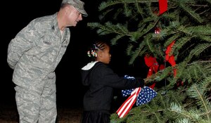 Col. Jim Forrest, Air Combat Command 633rd Medical Group deputy group commander, assists Jasmine E. Goodrum, daughter of Tech. Sgt. Aaron N. Goodrum, 633rd Air Base Wing noncommissioned officer in charge of chapel operations, in tying on a ribbon to the Christmas tree during the lighting ceremony at Langley Air Force Base, Va., Dec. 4, 2012. This was the 45th year running for this Christmas Tree Lighting Ceremony at Langley. (U.S. Air Force photo by Airman 1st Class Victoria Taylor/Released) 
