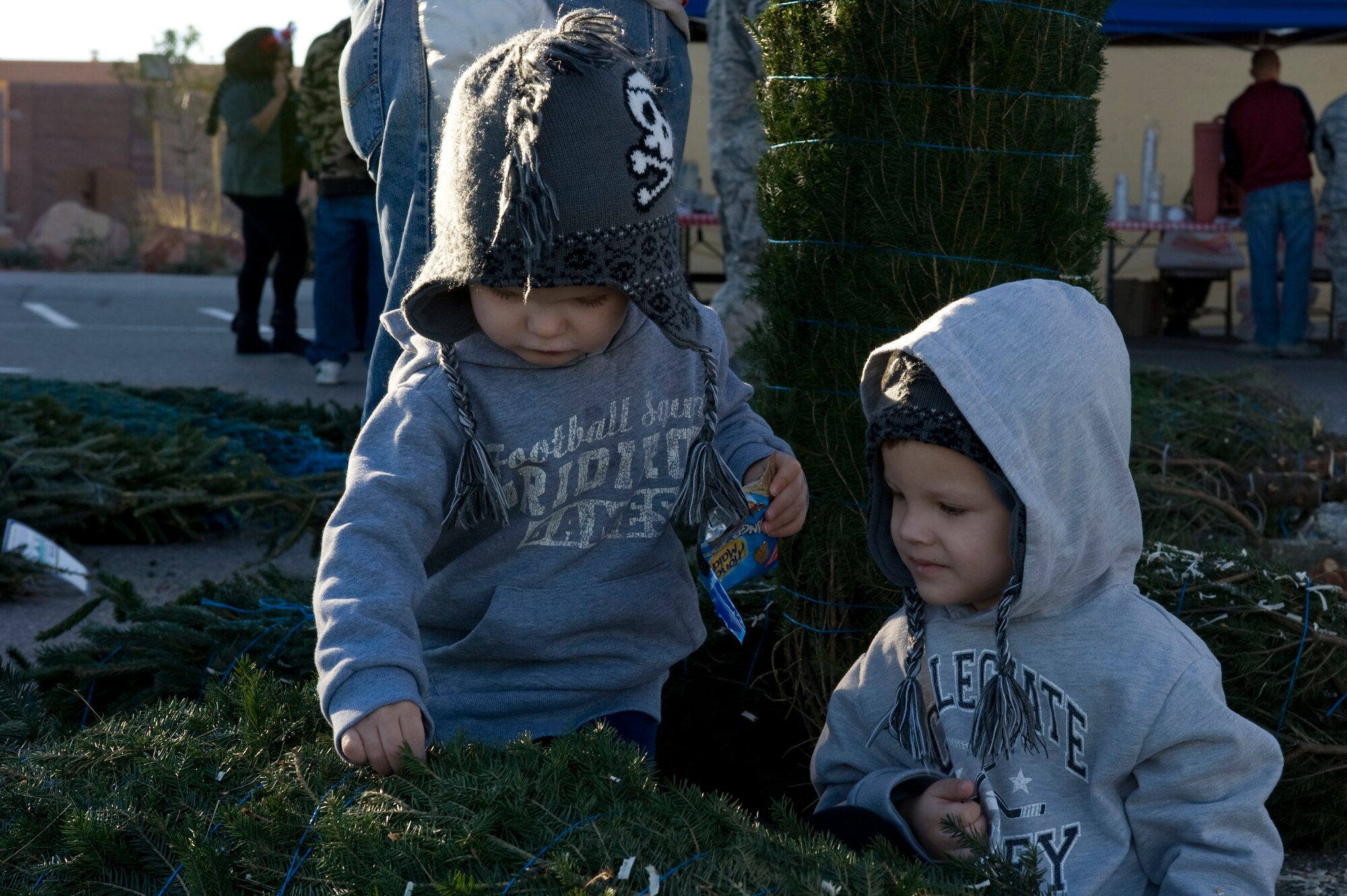 MacKeon and Wyatt Mullis play with a tree during the Trees for Troops event Dec. 7, 2012, at Nellis Air Force Base, Nev. Christmas tree farmers from around the country donated the trees for the event. (U.S. Air Force photo by Senior Airman Matthew Lancaster)