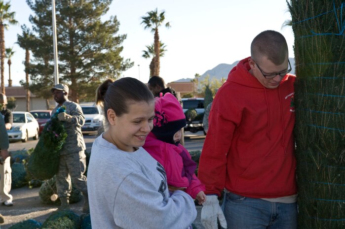 Airman 1st Class Brandon Fowler, 99th Civil Engineer Squadron pavement and equipment operator, holds the tree that Nicole Mullis and her family selected during the Trees for Troops event Dec. 7, 2012, at Nellis Air Force Base, Nev. This year, more than 100,000 trees from 29 states are expected to be delivered to military bases in the United States and overseas. (U.S. Air Force photo by Senior Airman Matthew Lancaster)