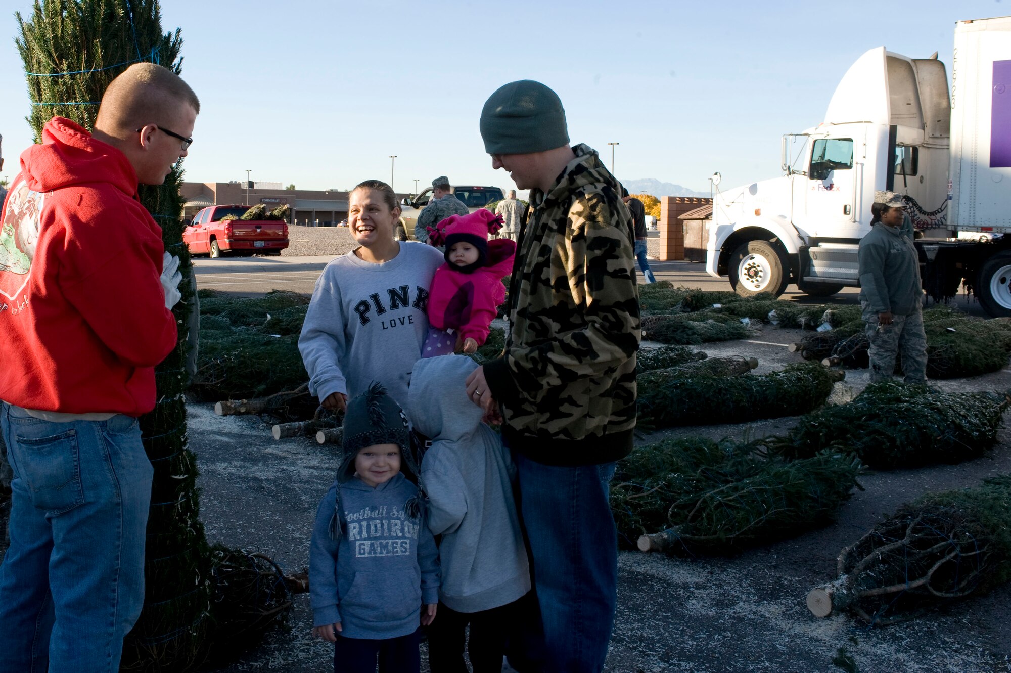 Airman 1st Class Brandon Fowler, 99th Civil Engineer Squadron pavement and equipment operator, assists Staff Sgt. Mike Mullis and his family to select a tree during the Trees for Troops event Dec. 7, 2012, at Nellis Air Force Base, Nev. The Trees for Troops program, sponsored by the Christmas SPIRIT Foundation and FedEx Corp, provided trees for active duty military members for the eighth consecutive year. (U.S. Air Force photo by Senior Airman Matthew Lancaster)