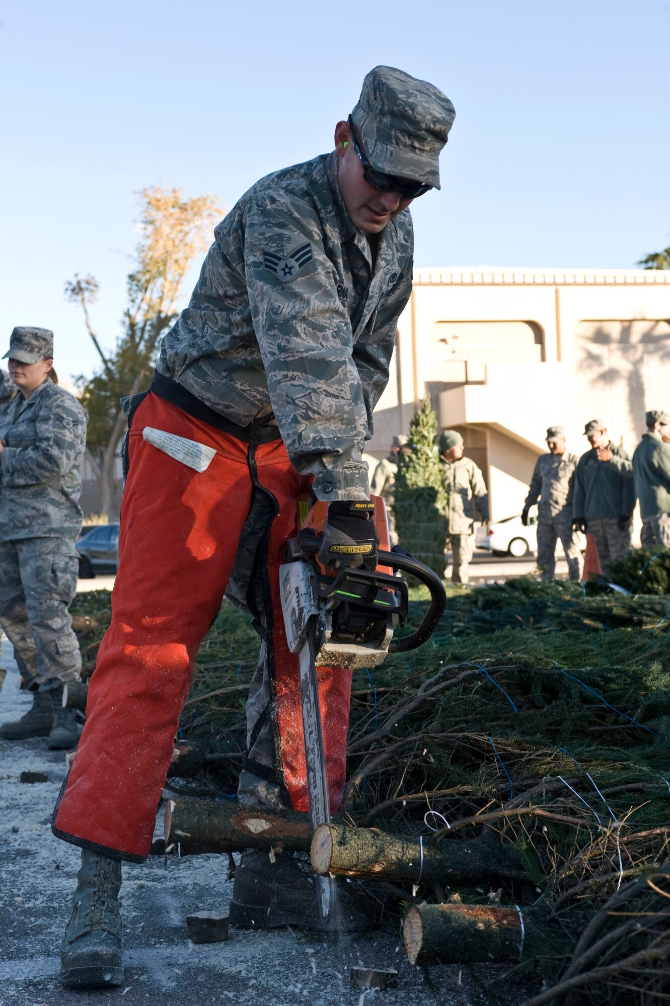 Senior Airman Andrew Perna, 99th Civil Engineer Squadron heavy equipment operator, saws the ends of Christmas trees during the Trees for Troops event Dec. 7, 2012, at Nellis Air Force Base, Nev. Exactly 808 trees were donated to Nellis to be given to active duty military members. (U.S. Air Force photo by Senior Airman Matthew Lancaster)