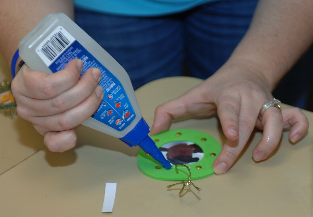 A relative of a fallen Soldier applies glue onto an ornament which will hang on the Survivor Outreach Services’ holiday remembrance tree, at the 733rd Mission Support Group headquarters, Dec. 4, 2012. SOS is a program dedicated to families of fallen Service members by providing support and standardized services. (U.S. Air Force photo by Airman 1st Class R. Alex Durbin/Released)