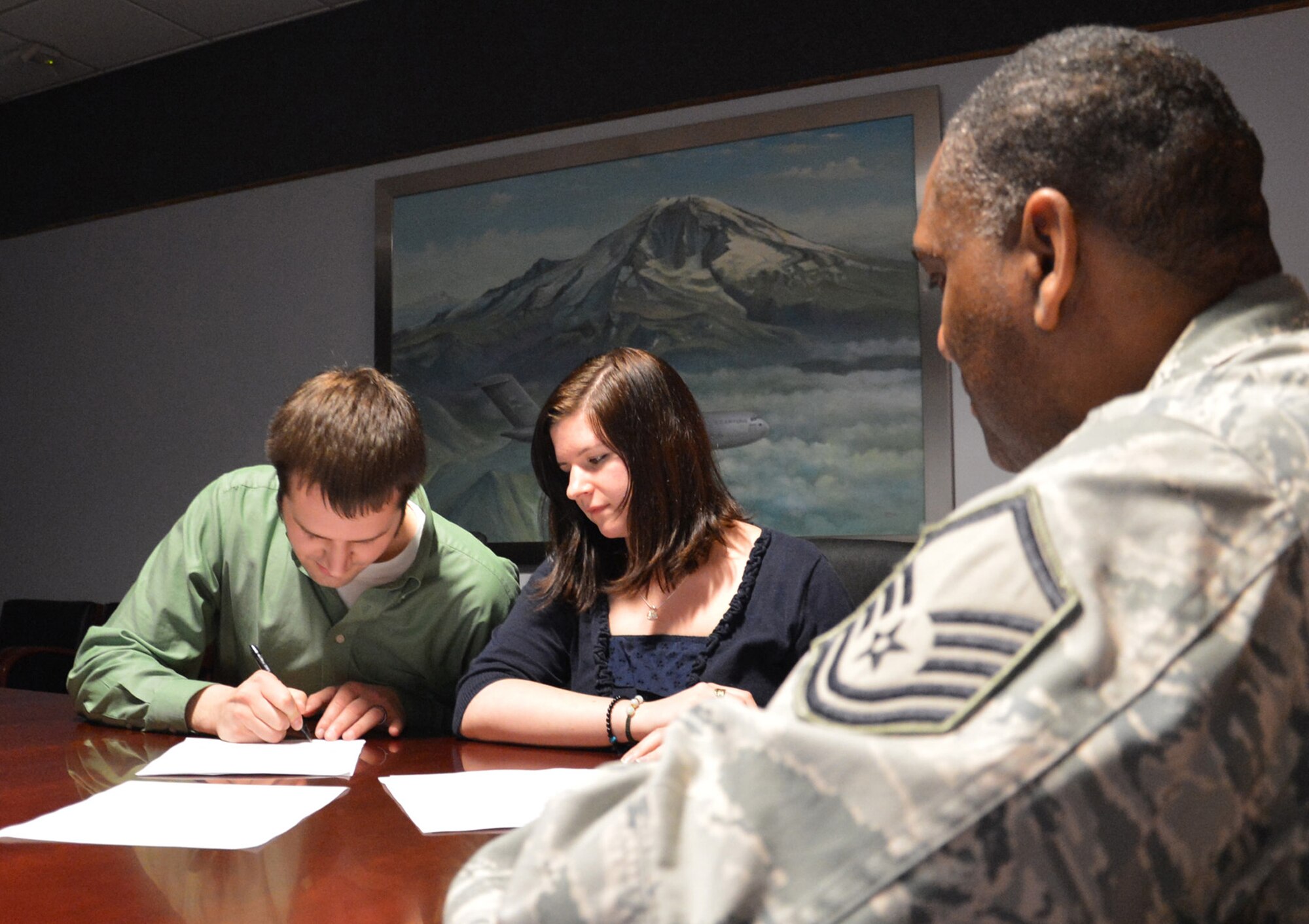 Eric (left) and Ashlee (center) Todd fill out enlistment paperwork before taking their oath of enlistment with the Air Force Reserve at the 446th Airlift Wing headquarters building at McChord Field, Wash., Nov. 30, 2012. Originally, Ashlee was going to be the only enlistee, but thanks to Master Sgt. Charles Loftland (right), a recruiter for the 446th AW, Eric was sold on the honor of joining the Reserve with his wife. (U.S. Air Force photo by Master Sgt. Jake Chappelle)