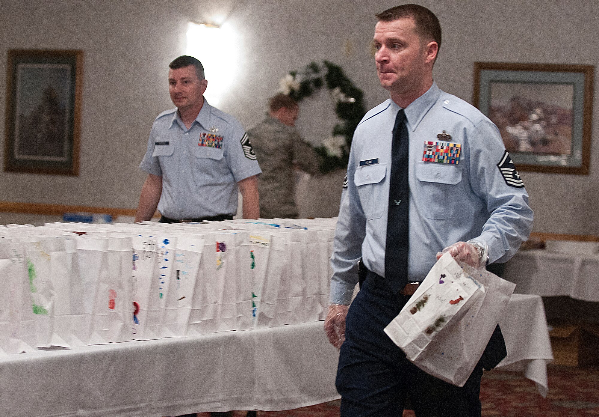 Master Sgt. Daniel Flint, 90th Force Support Squadron first sergeant, carries bags of cookies past a line of bags waiting to be filled. Flint took part in the annual F. E. Warren Air Force Base cookie drive Dec. 3, which provides goodies for the Airman living in the base dormitories. (U.S. Air Force photo by R.J. Oriez)