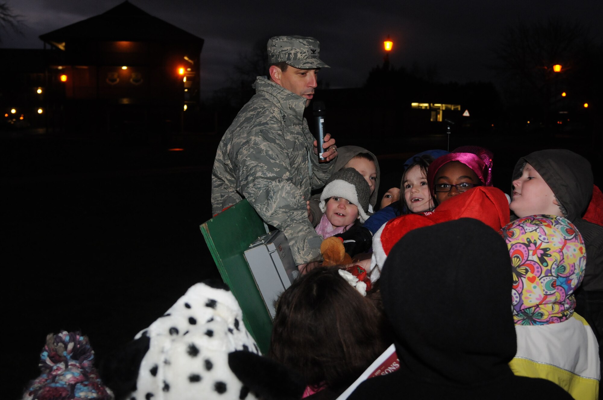 Col. Christopher Kulas, 100th Air Refueling Wing commander, with the help of children from RAF Mildenhall, flips the switch illuminating the Christmas tree during the base Christmas tree lighting ceremony Dec. 7, 2012, at RAF Mildenhall, England. The event celebrates the beginning of the holiday season for RAF Mildenhall. (U.S. Air Force photo by Airman 1st Class Kelsey Waters/Released) 