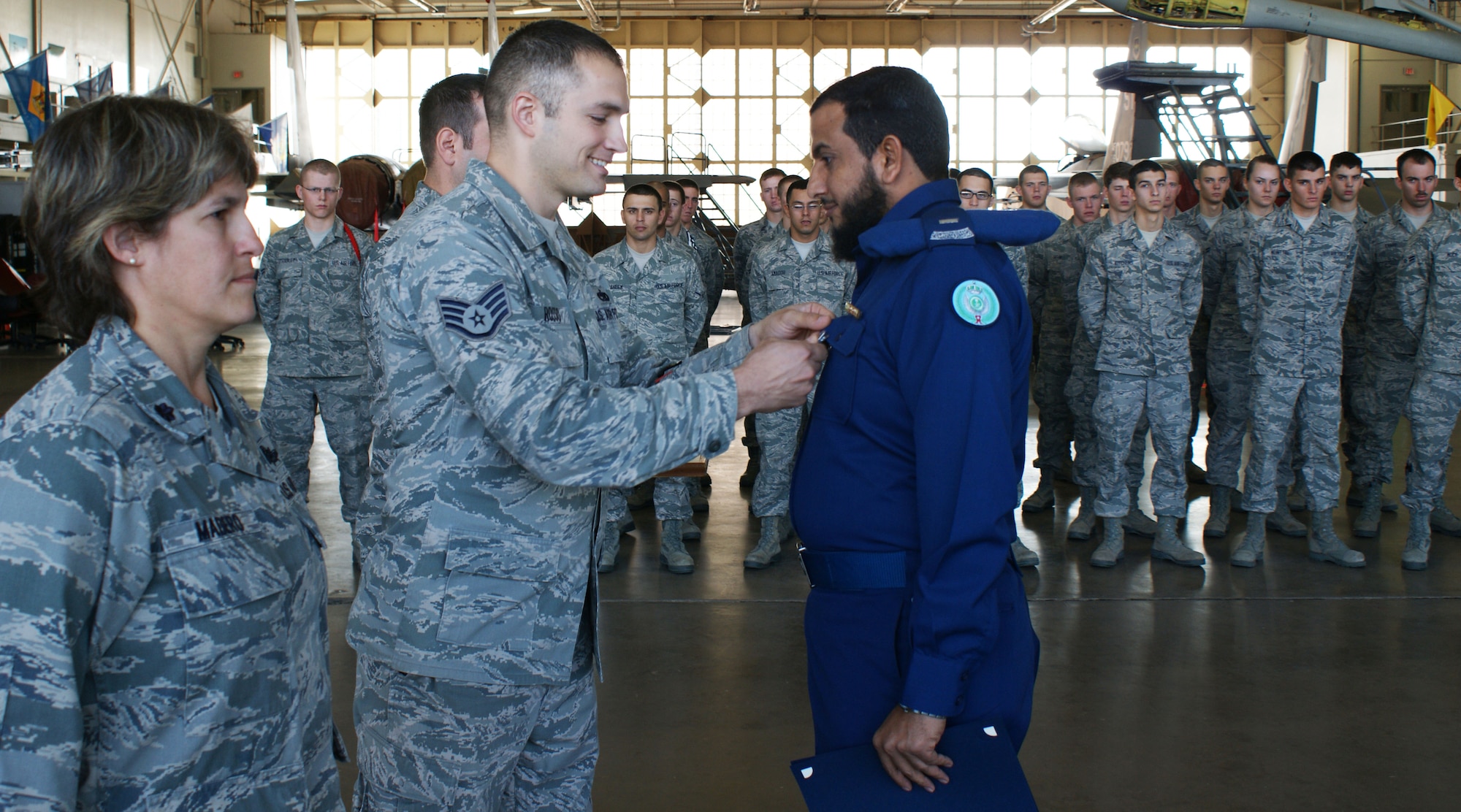 Staff Sgt. Patrick Rosso, 364th Training Squadron electrical and environmental apprentice course instructor, pins the aircraft maintenance badge on Royal Saudi Air Force (RSAF) Chief Master Sgt. Muftah Alessa  during the Electrical and Environmental apprentice course graduation ceremony at Sheppard Air Force Base, Texas, Dec. 7, 2012.   Alessa became just the second RSAF student to graduate as the "Top Graduate" of the course.  (U.S. Air Force photo/Dan Hawkins) 