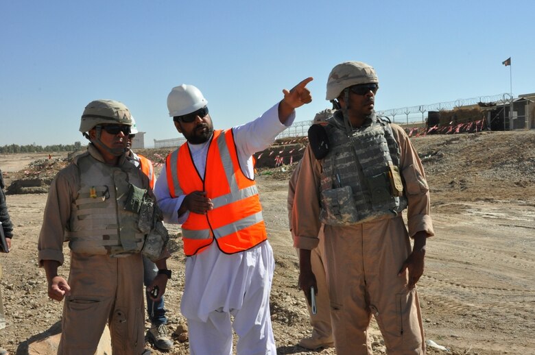 Benny Apuya, (far left) a quality assurance and construction representative and Ira Dorsett, (far right) both with the Afghanistan Engineer District-South meet with a contractor on the Kandahar Regional Military Training Center project Nov. 18. Apuya and Dorsett visit the site several times a week to make sure construction complies with plans and specifications as well as International Building Code standards. 