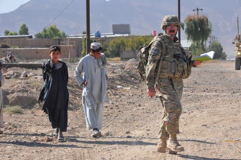 Bill Hollingsworth P.E., a civil engineer from the 565th Engineer Detachment Forward Engineer Support Team - Advance visually inspects the unpaved road at Shur Andam Industrial Park, Nov. 7, 2012, as two boys from a local village follow him. The goal is for the Government of the Islamic Republic of Afghanistan and/ or a donor nation to use the data Hollingsworth provides to build a paved road at the industrial park.