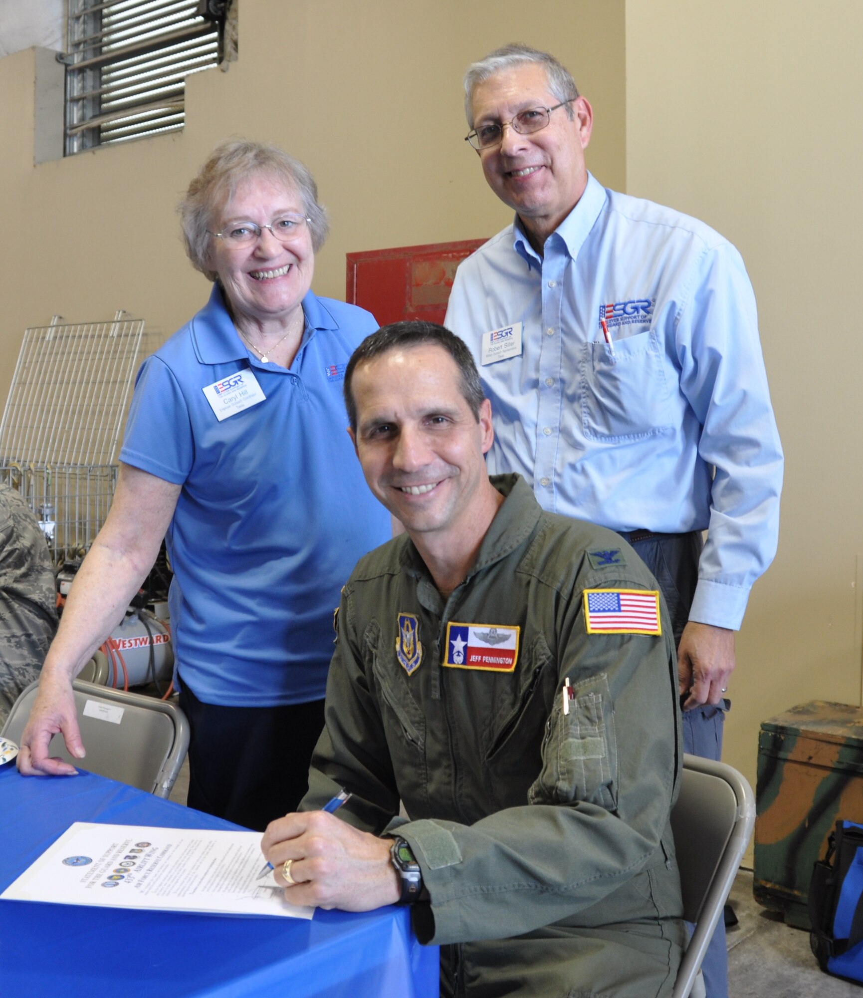 Caryl Hill and Robert Siler of the Texas Committee of Employer Support for the Guard and Reserve witness Col. Jeffery T. Pennington, 433rd Airlift Wing commander, sign a document in support of the ESGR.  Over 40 employers attended the 19th annual Employers' Day sponsored by the Alamo Wing at Joint Base San Antonio-Lackland, Texas on Dec. 8, 2012. (Air Force photo by Tech Sgt. Carlos J. Trevino) 