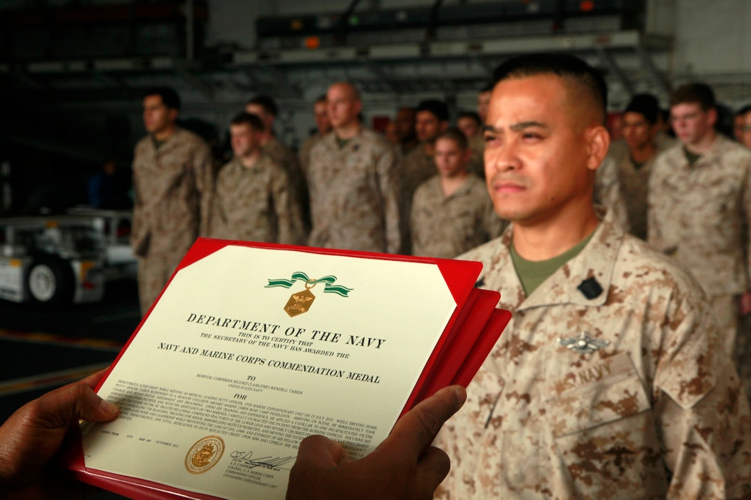Hospital Corpsman 2nd Class Wendell Tabios, hospital corpsman, Command Element, 15th Marine Expeditionary Unit, stands at the position of attention before being awarded the Navy and Marine Corps Commendation Medal during the Command Element’s promotion and awards ceremony in the hangar bay of the USS Peleliu, Dec. 1. Tabios received the award for his immediate medical response after a head-on collision on Camp Pendleton in July, where he saved a life. The 15th MEU is deployed as part of the Peleliu Amphibious Ready Group as a U.S. Central Command theater reserve force, providing support for maritime security operations and theater security cooperation efforts in the U.S. 5th Fleet area of responsibility. Tabios, 37, is from Cavite, Philippines. (U.S. Marine Corps photo by Cpl. John Robbart III/Released)
